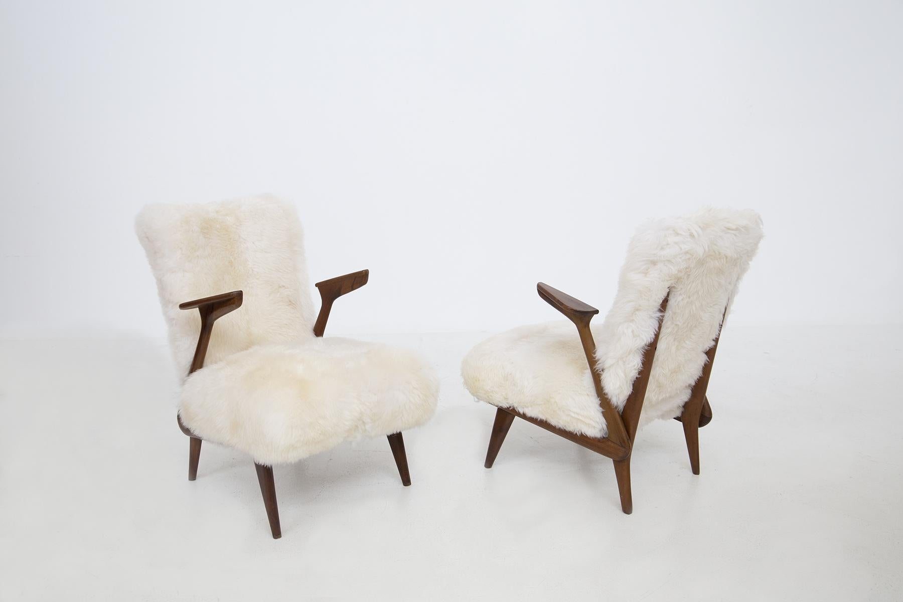 Elegant pair of Italian armchairs attributed to Giuseppe Scapinelli from the 1950s. The armchairs are made of walnut wood. The armchairs have a linear and anthropomorphic shape where the armrest vibrates towards each other with triangular shape .