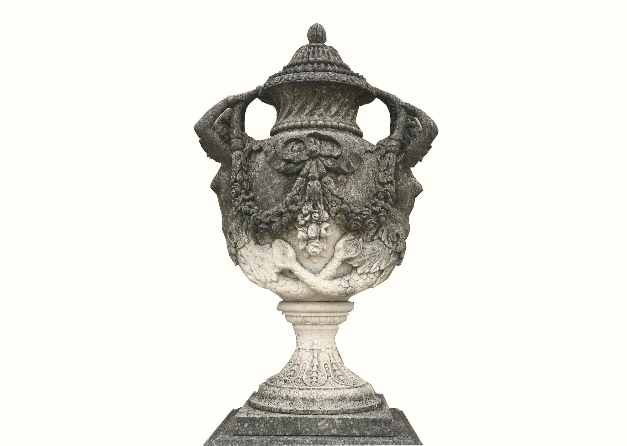 Impressive pair of hand carved vases in the 18th century style, the cover with fruit finial, above an ovoid body adorned with Nereid handles and festoons, raised on circular foot and square base, on square paneled pedestal.
Executed in a highest