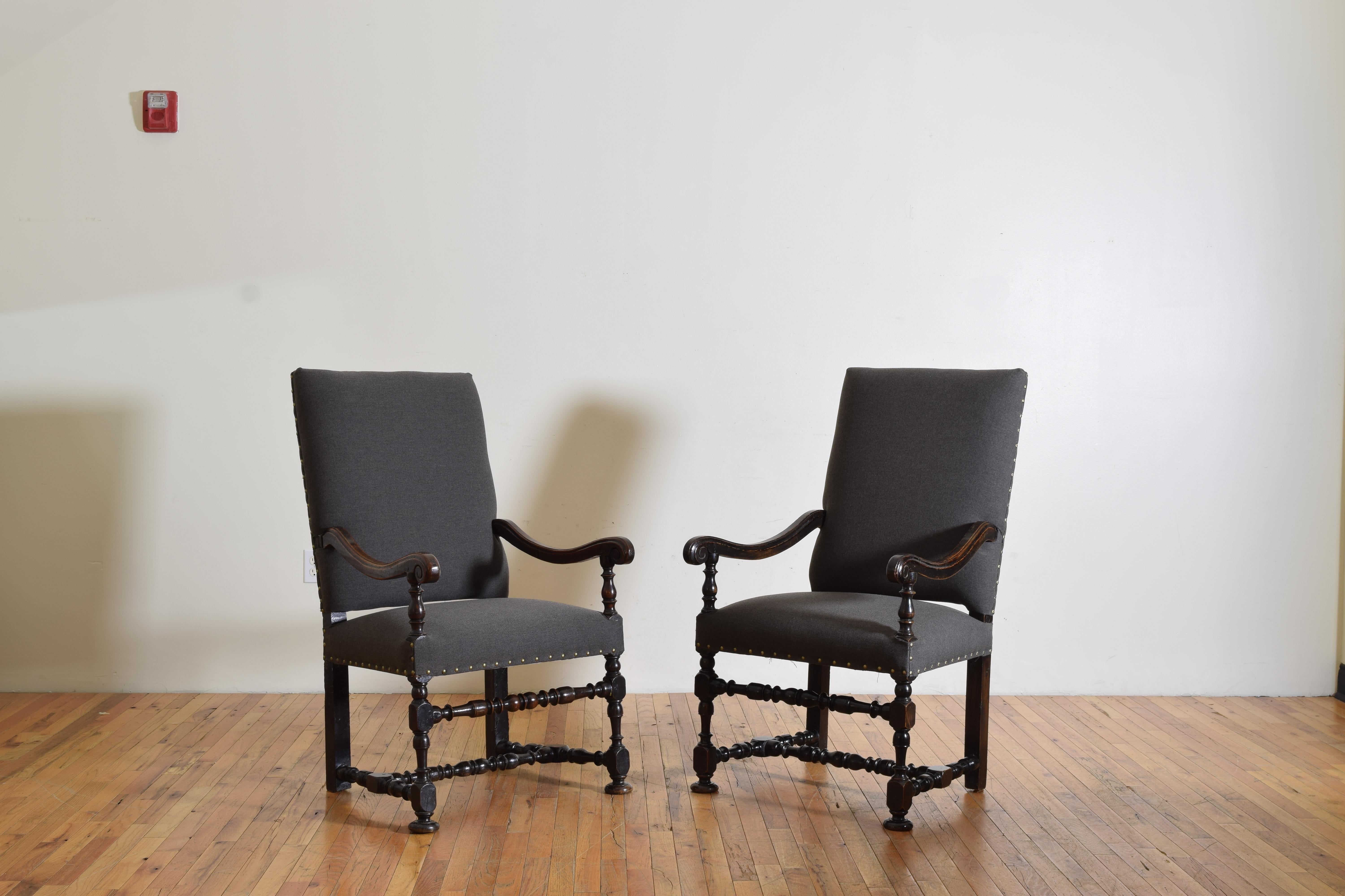 Having slightly leaning rectangular backrests, one curiously with two very small iron rings on its back, with shaped arms and downturned handles with turned arm supports, the tight upholstered seats resting upon turned frames joined by h-form