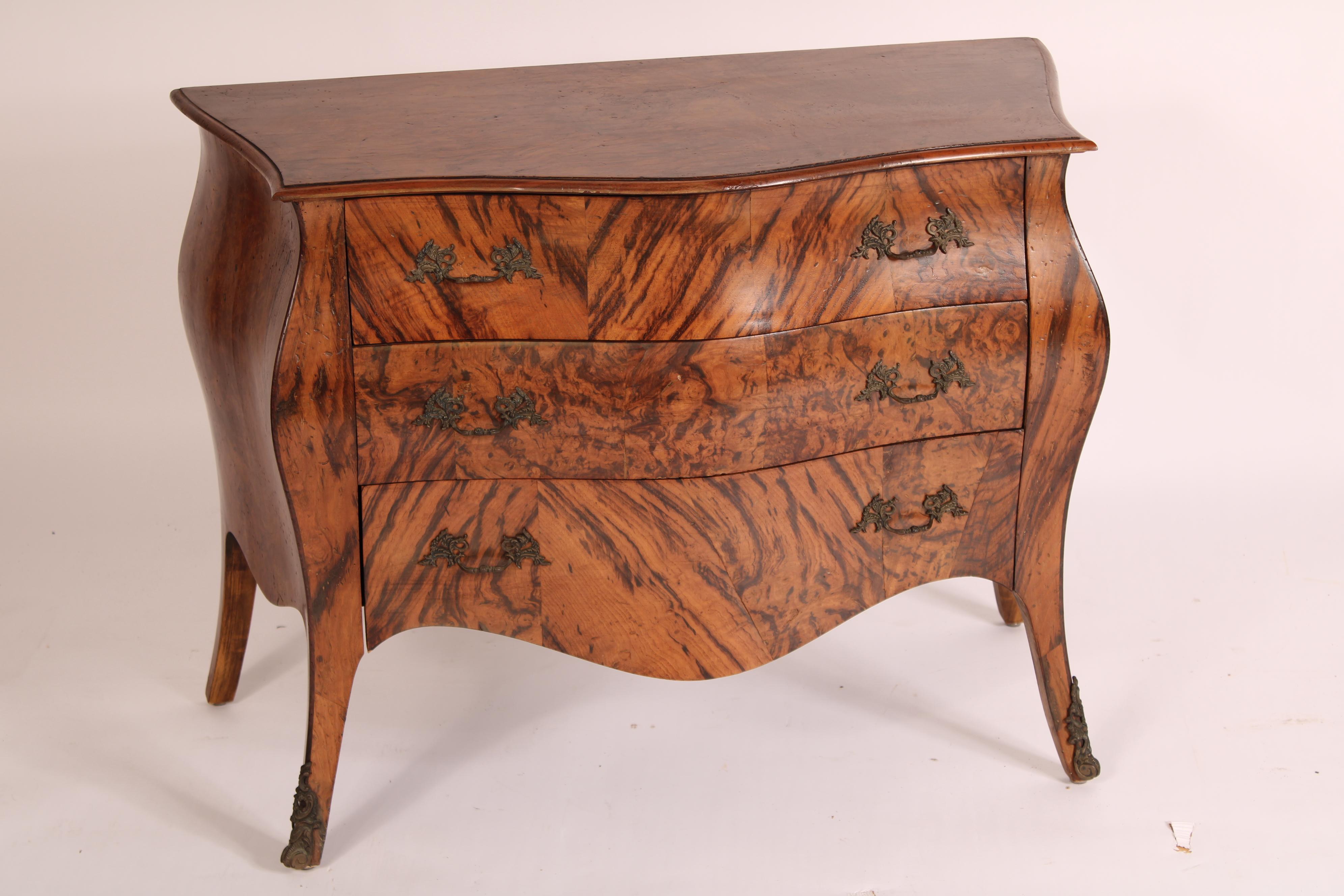 Coppia di bombe commodini in legno di radica in stile Luigi XV, anni '80 circa. Con un piano in legno burattato con bordo anteriore a forma di serpentina, 3 cassetti con ferramenta in ottone in stile foliato, appoggiati su piedi strombati che