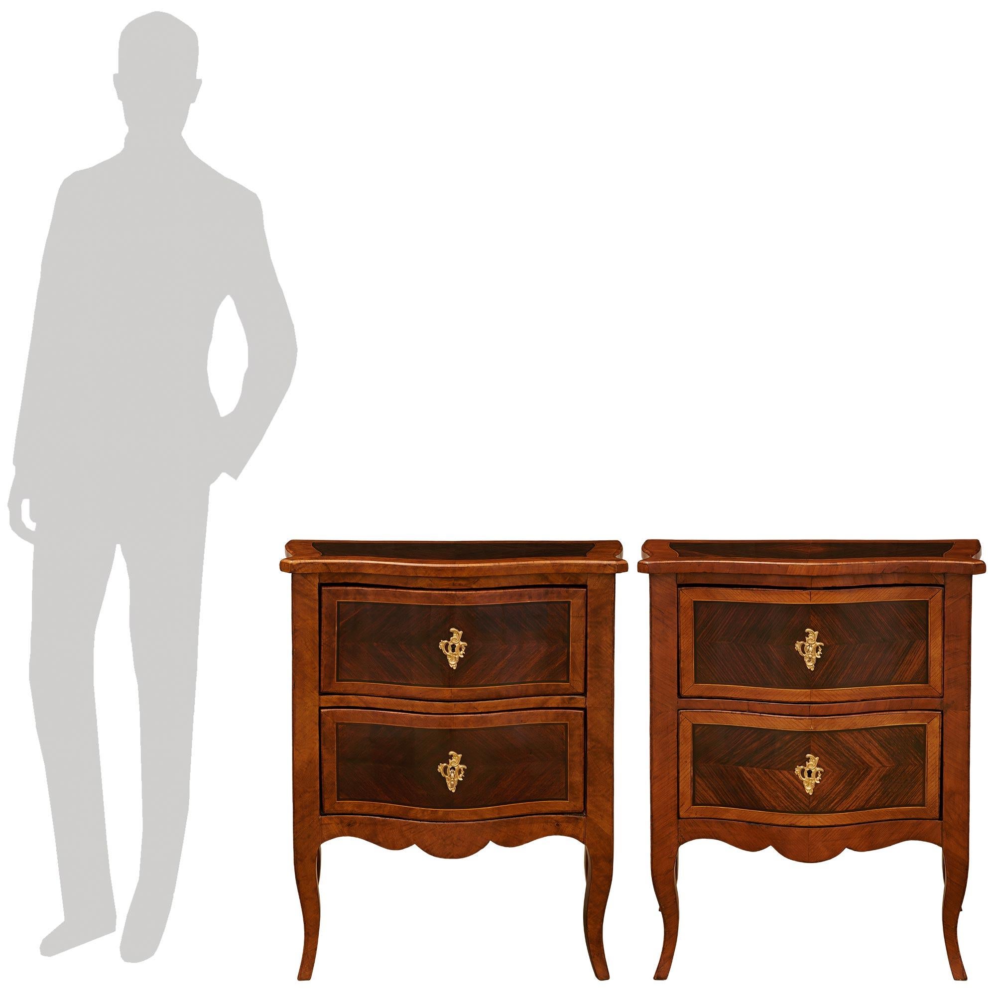 Une paire élégante et très décorative de commodes italiennes du début du 19ème siècle de style Louis XV en noyer, bois de roi et bronze doré. Chaque table d'appoint/coffre merveilleusement détaillé est surélevé par de minces pieds cabriole flanquant