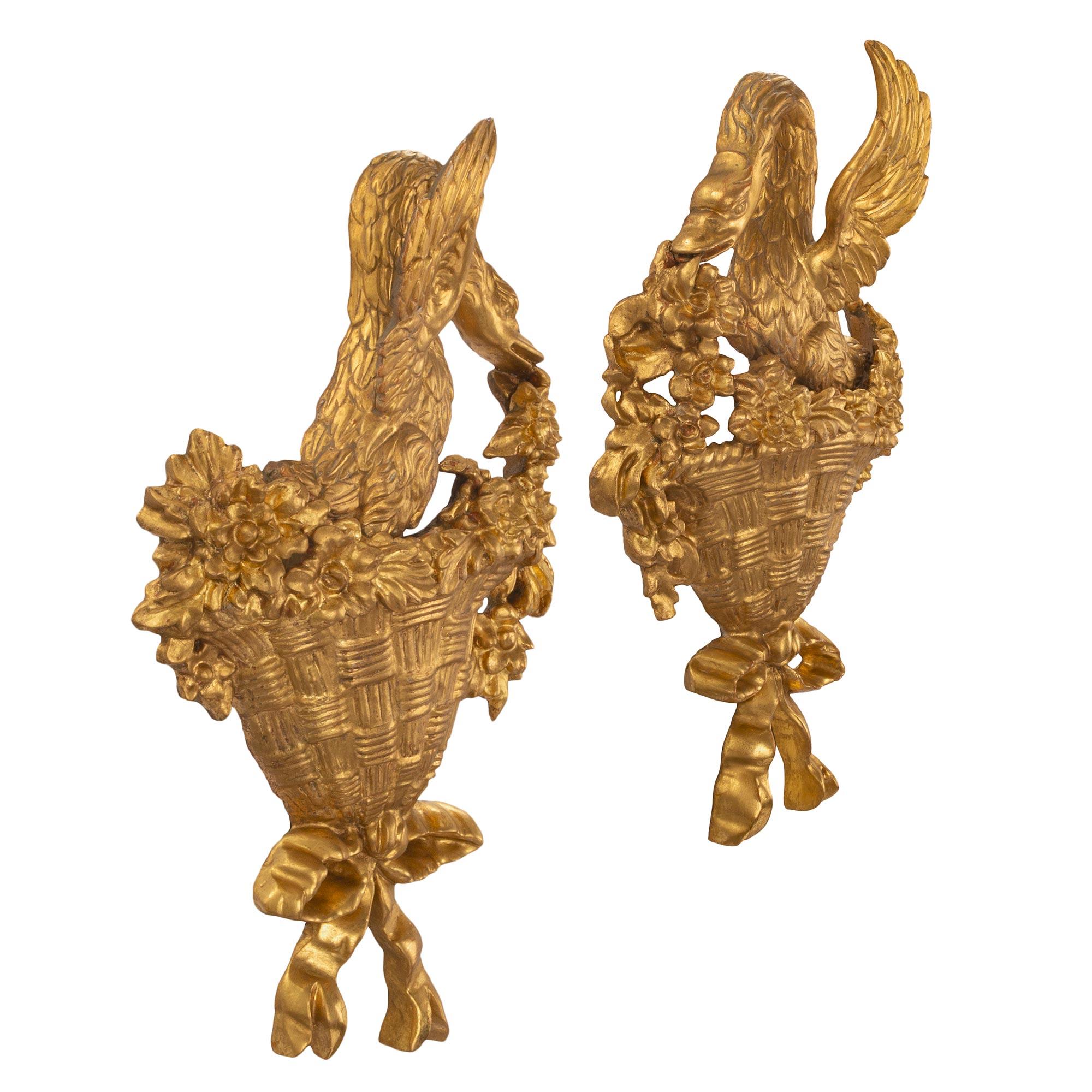 A beautiful and most decorative true pair of Italian Louis XVI st. carved giltwood wall decor. Each decorative element is centered by a charming bottom tied bow below a wonderfully executed woven basket. Two richly carved swans are seated among fine