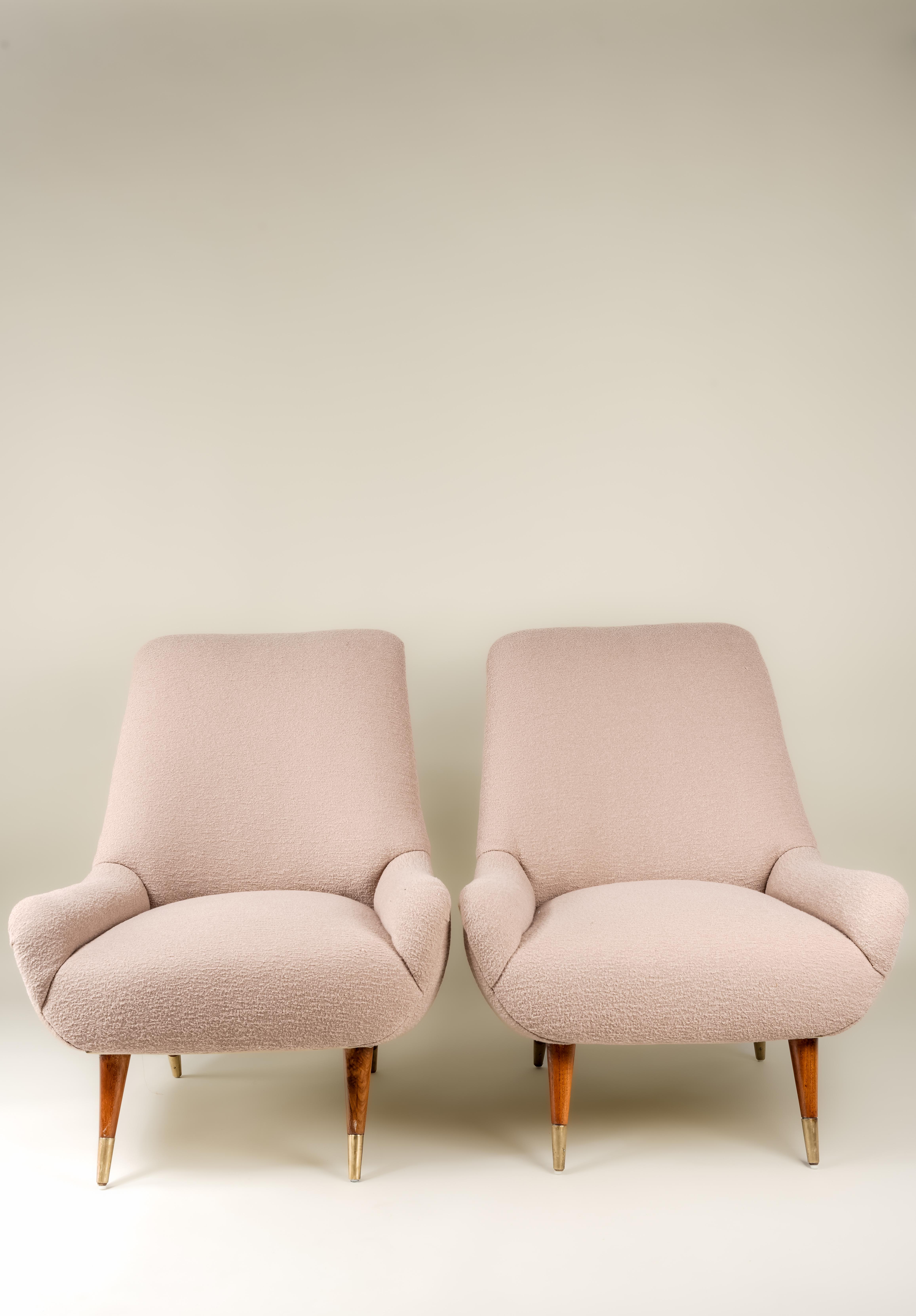 This pair of midcentury Italian lounge chairs features new cashmere boucle upholstery in a buff cream color. The sleek, streamlined chairs feature tapered wooden legs with brass slipper cups. Vintage condition with new upholstery. Wear consistent