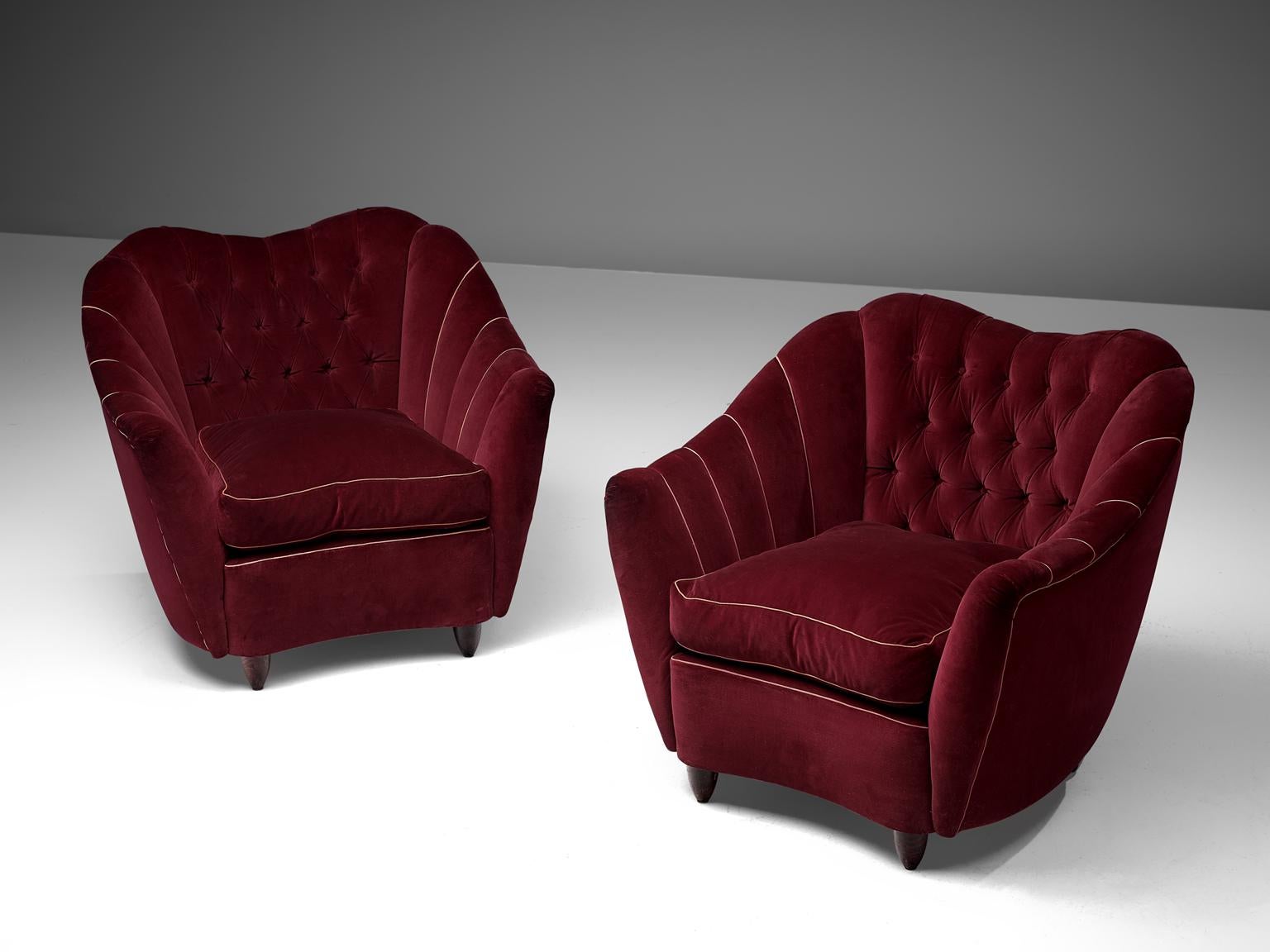 Pair of club chairs, velvet and wood, Italy, 1950s.

Theatrical set of lounge chairs being a wonderful example of Italian design from the 1950s. The chairs are bold and curvy, yet very elegant. The backrest is tufted and lined, which emphasizes