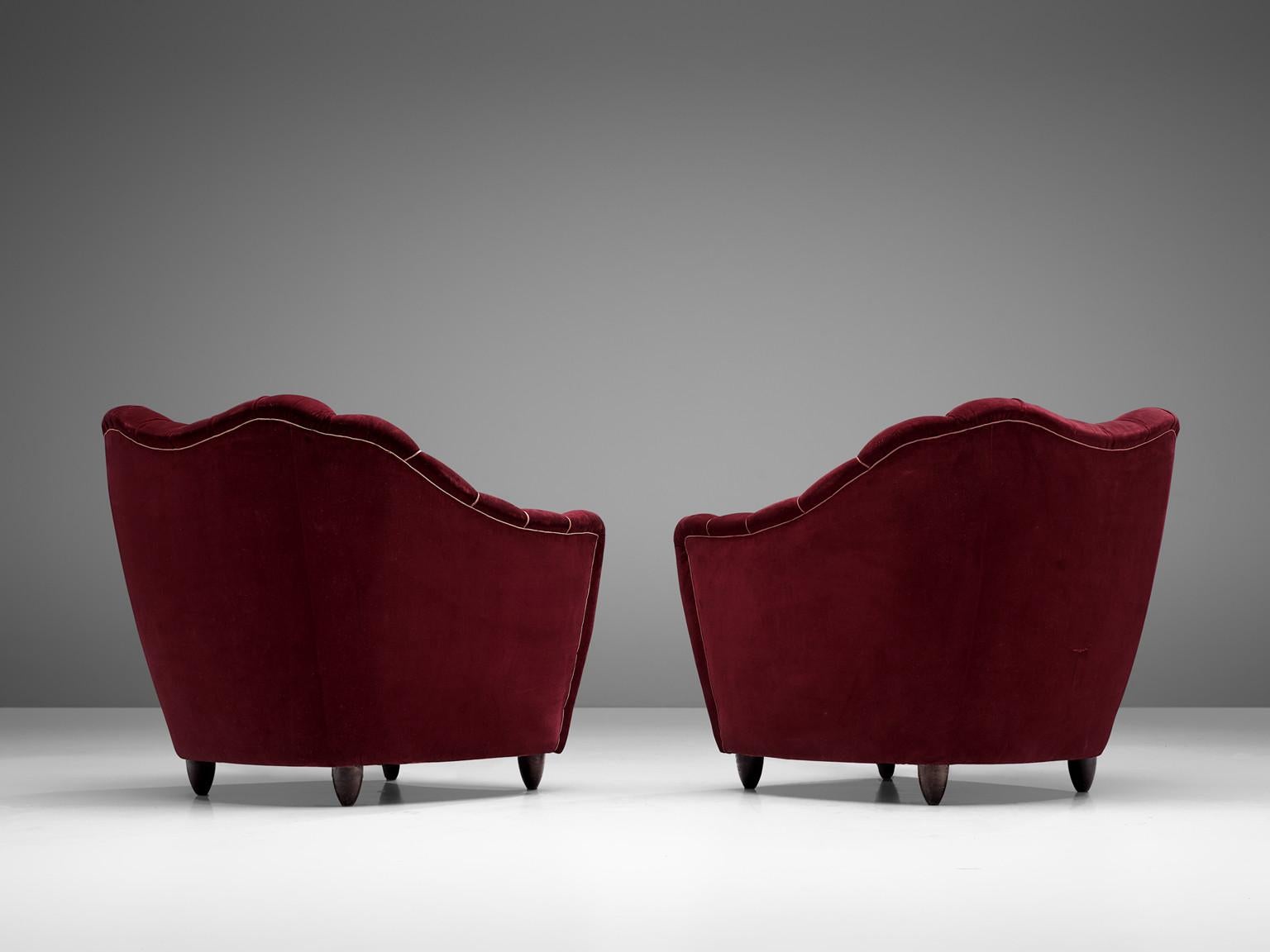 Pair of club chairs, velvet and wood, Italy, 1950s.

Theatrical set of lounge chairs being a wonderful example of Italian design from the 1950s. The chairs are bold and curvy, yet very elegant. The backrest is tufted and lined, which emphasizes the