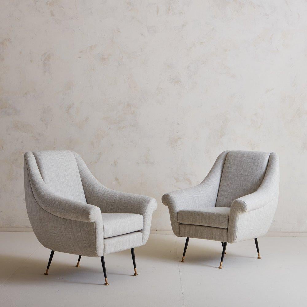 A pair of Italian Mid Century Lounge chairs featuring clean, modern lines; similar in style to designs by Marco Zanuso. These elegant chairs were newly reupholstered in a striated wool blend fabric and stand on four angled, tubular black metal legs