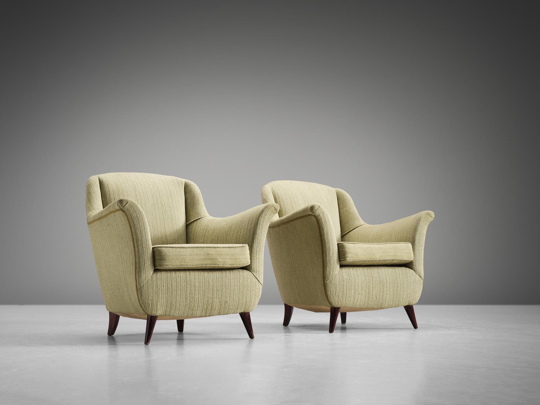 Pair of armchairs, green fabric, wood, Italy, 1950s.

This set of lounge chairs is both voluptuous and grand as they are comfortable. The chairs have semi high wingbacks and feature green fabric and small tapered wooden legs. Typical curvy, bold