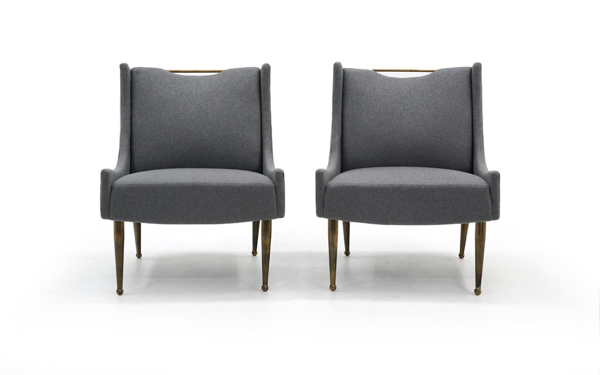 Set of two Italian midcentury armchairs. Expertly reupholstered in a light / medium grey fabric. The legs on these chairs are solid brass with years of patina. We would be happy to polish the legs to a shine if you desire.