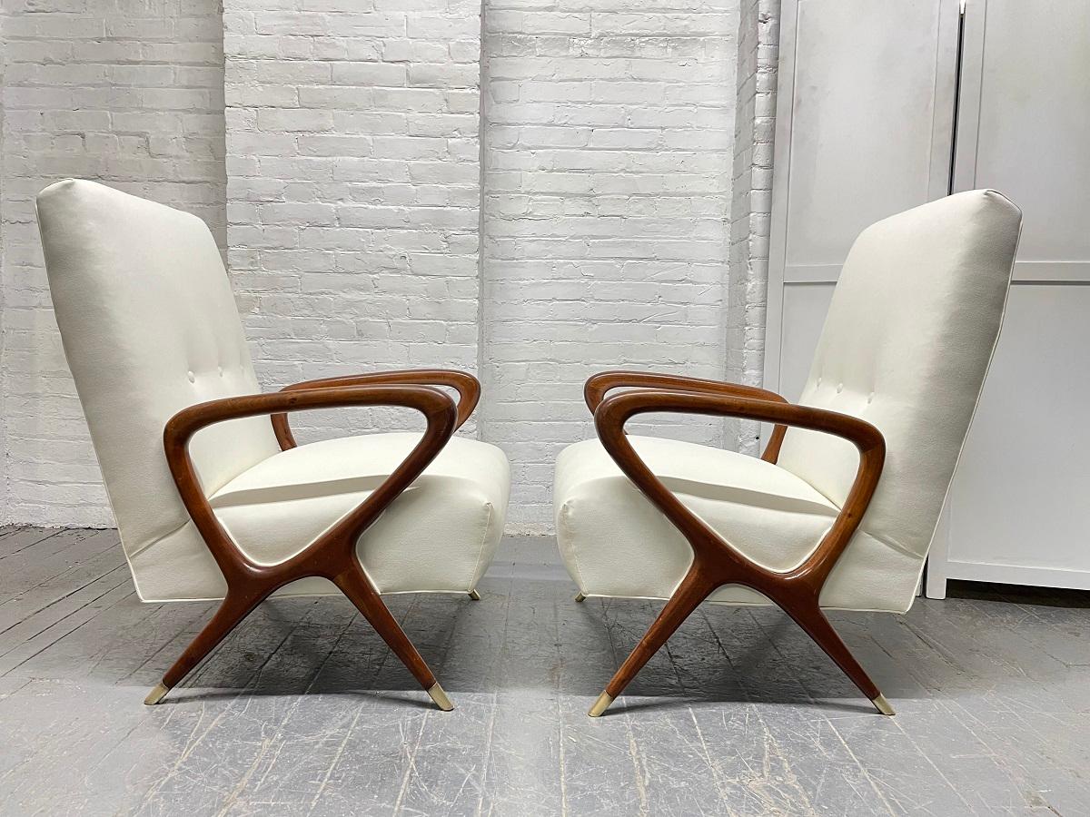 1960s Pair of Italian lounge chairs in the style of Gio Ponti. The chairs have sculptural, solid walnut frames with brass sabots. 
There is a matching loveseat sold separately.       