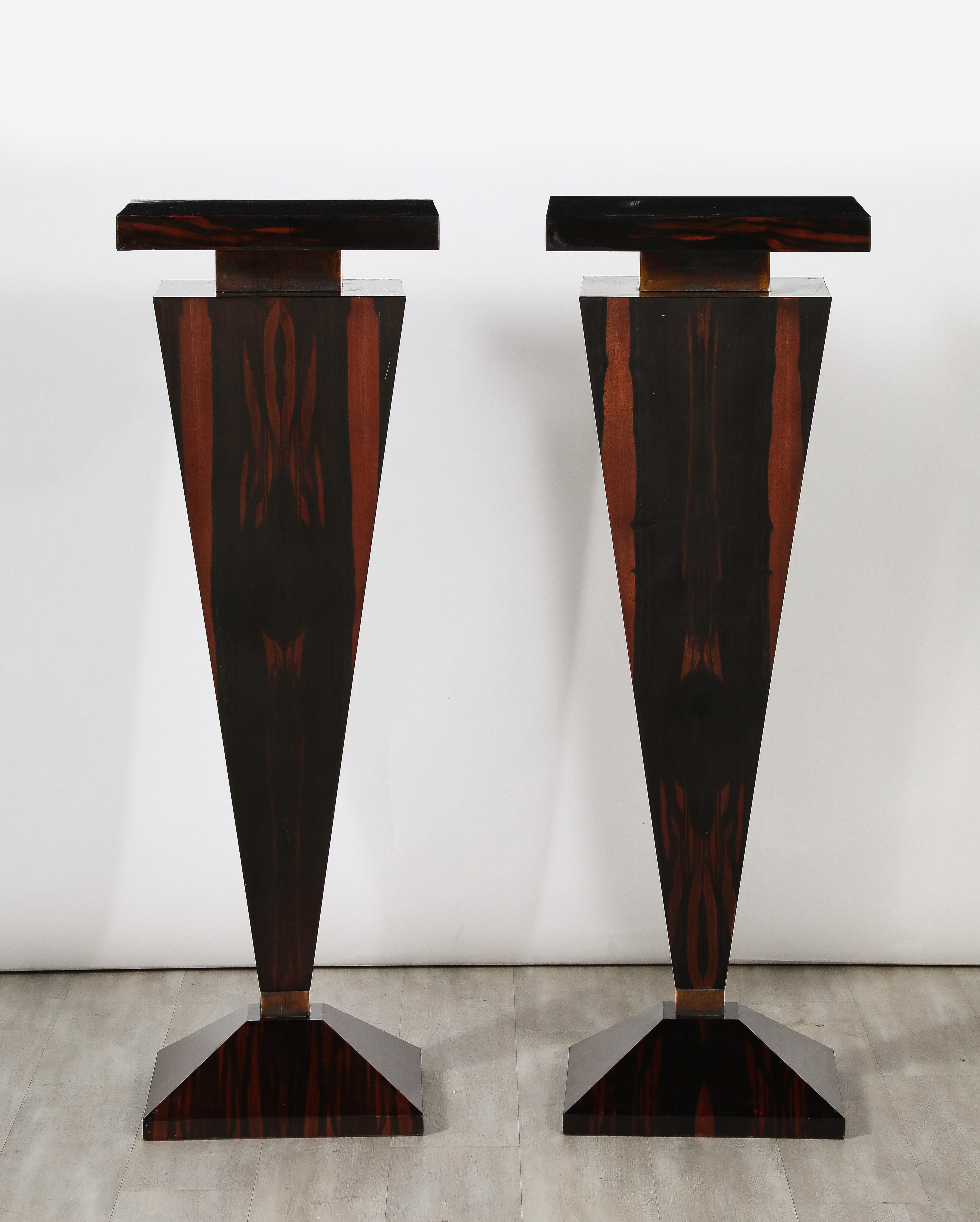 A dramatic grand scale pair of pedestals in Macassar ebony veneer with a high gloss finish, the tops and base with banding of gilt metal. These were commissioned for a private home in Northern Italy, circa 1970's.  They stand alone as stunning