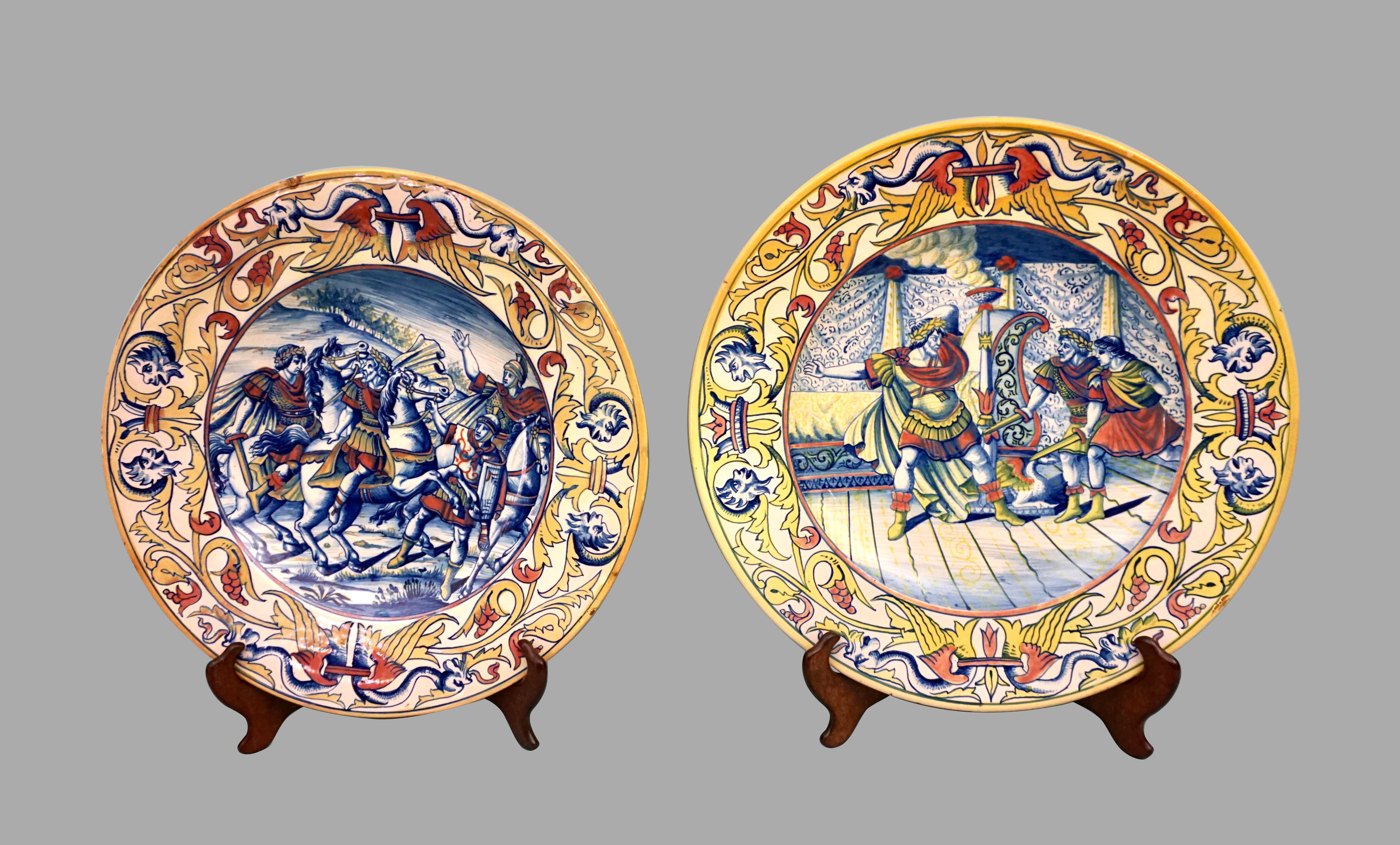 A near pair of Italian maiolica plates depicting battle scenes of Roman soldiers one with garrisons on horseback the other possibly an allegorical tale of the assassination of a Roman noble or emperor. Both are well-executed with a fluency of line,