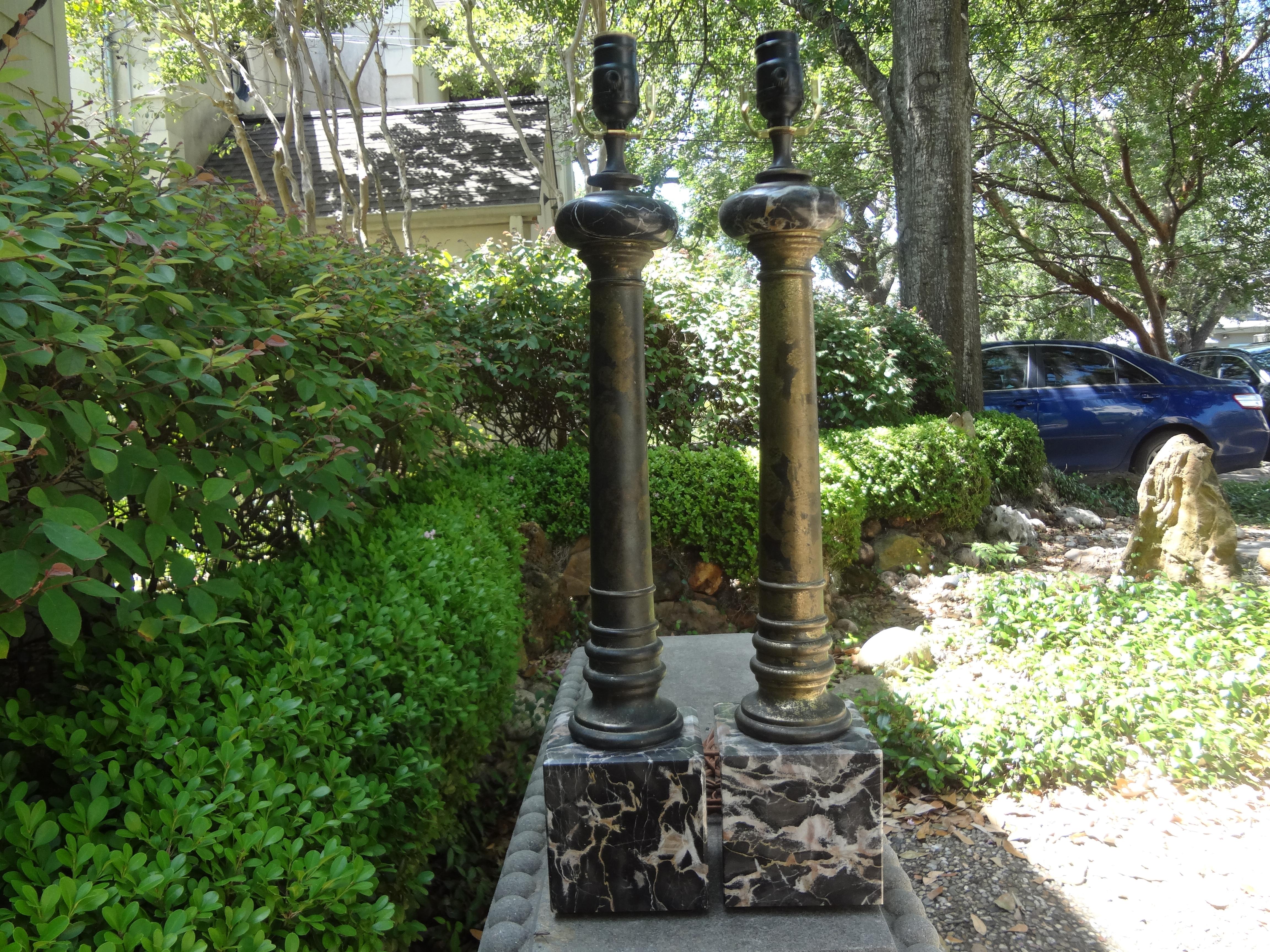 Lovely pair of vintage Italian neoclassical style marble and tole table lamps possibly by Marbro. This great pair of Hollywood Regency column lamps are executed with bases of large blocks of marble, marbleized tole columns and topped with marble
