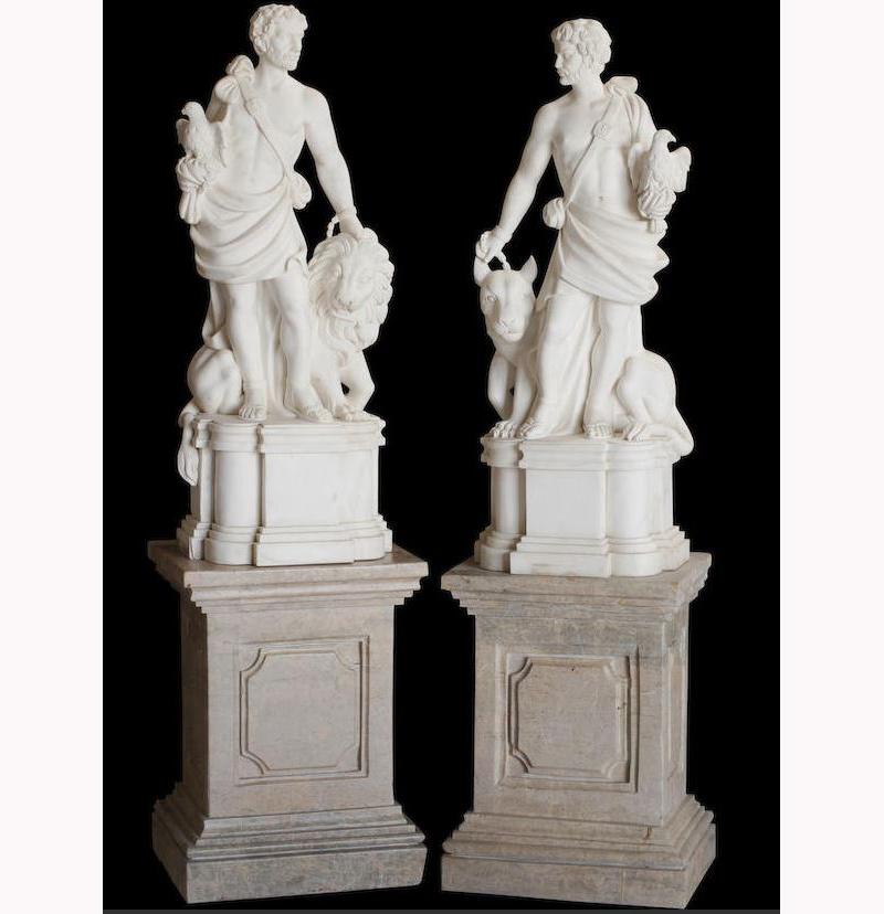 Impressive pair of Italian white marble statues depicting Roman Hunters.
Mid-20th century.

Intricately carved opposing figures, each dressed in a draping cloth, one hand clutching a bird and the other with a leash, one hunter accompanied by a
