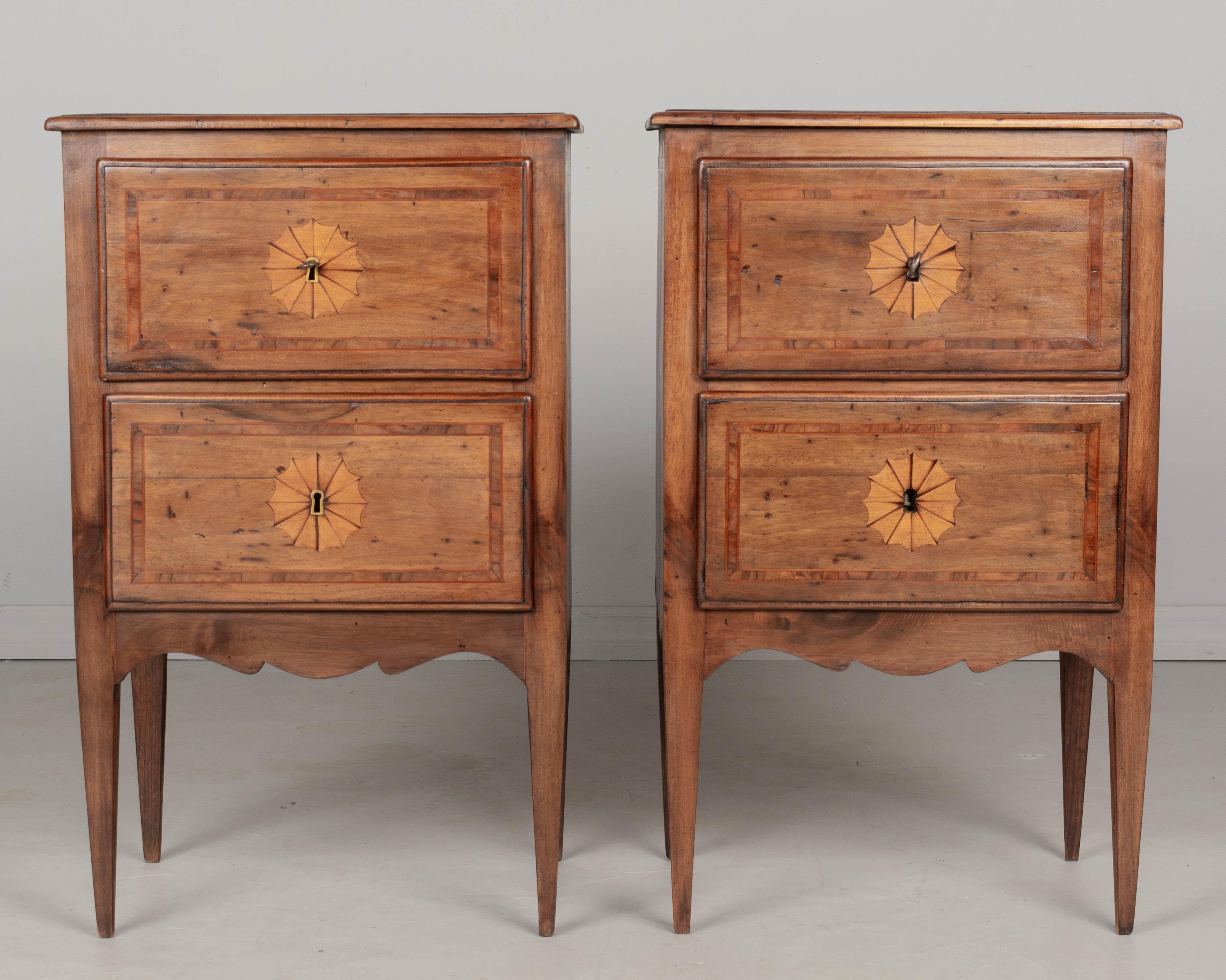 A pair of early 20th century Italian marquetry commodito, or nightstands, with inlaid veneer of walnut. Two dovetailed drawers, each with working lock and key. Two escutcheons are missing. Circa 1900-1920.  Sign of old wood worms but not