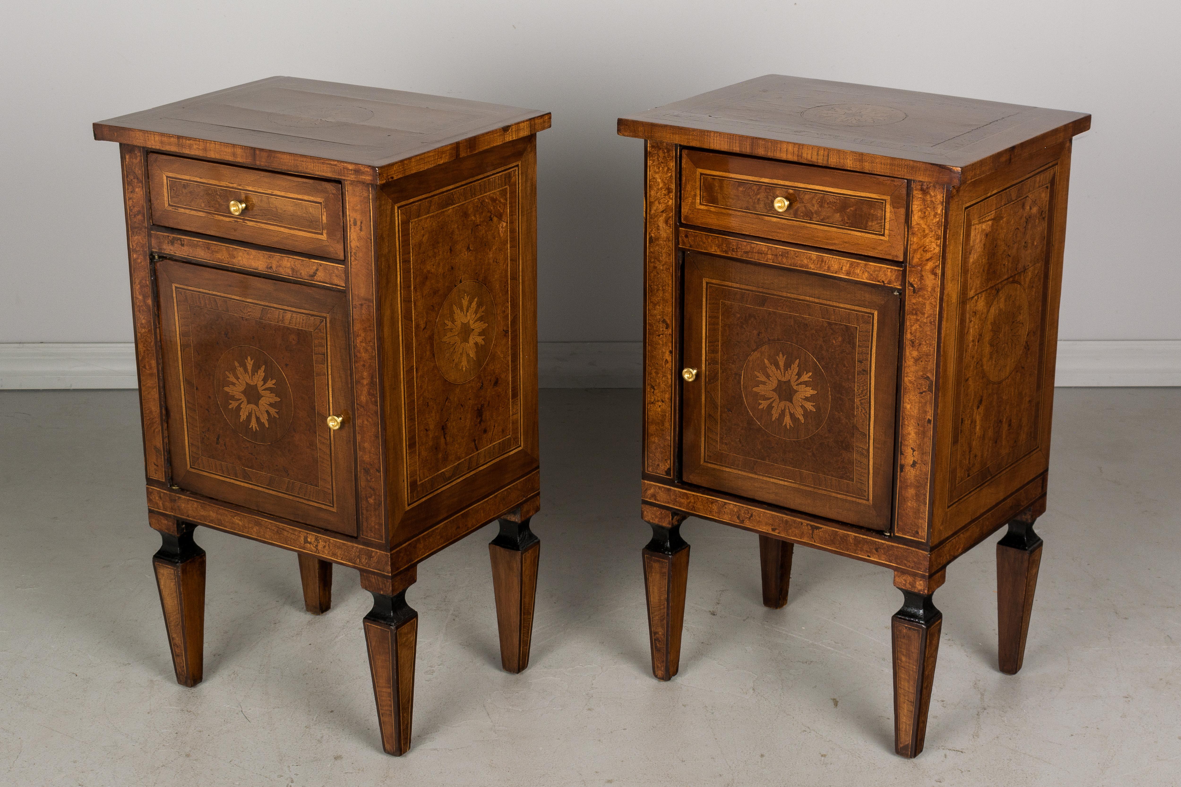 A near pair of Italian marquetry commoditos, or nightstands, with inlaid veneers of walnut and various woods and ebonized trim. French polish finish. The top, front and sides are decorated with central foliate medallions. Each with a single drawer