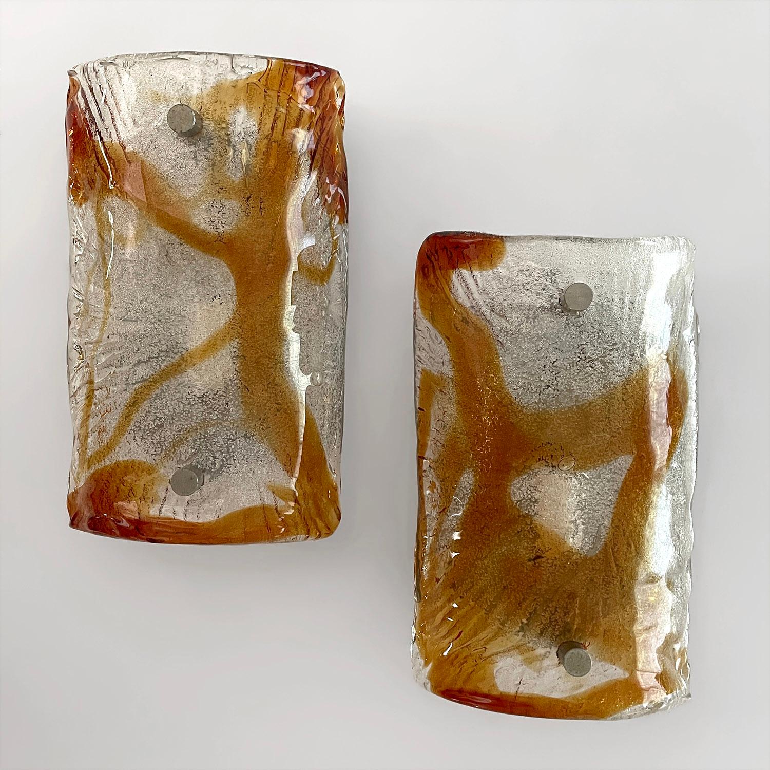 Pareja de apliques de cristal de Mazzega Murano
Italia, años 70 
Cada candelabro tiene una hermosa pantalla arqueada de cristal de Murano única en su patrón y composición
Las formas abstractas de cristal ámbar son el contraste perfecto contra el