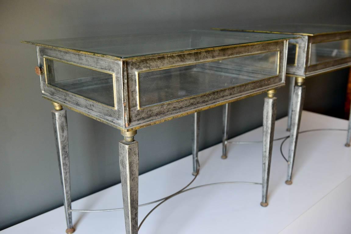 Pair of Italian metal and glass side tables, circa 1970. Great patina to the metal with self adjusting feet and doors that open on either side. Original glass. Signed on underside.
Each measure 28.5