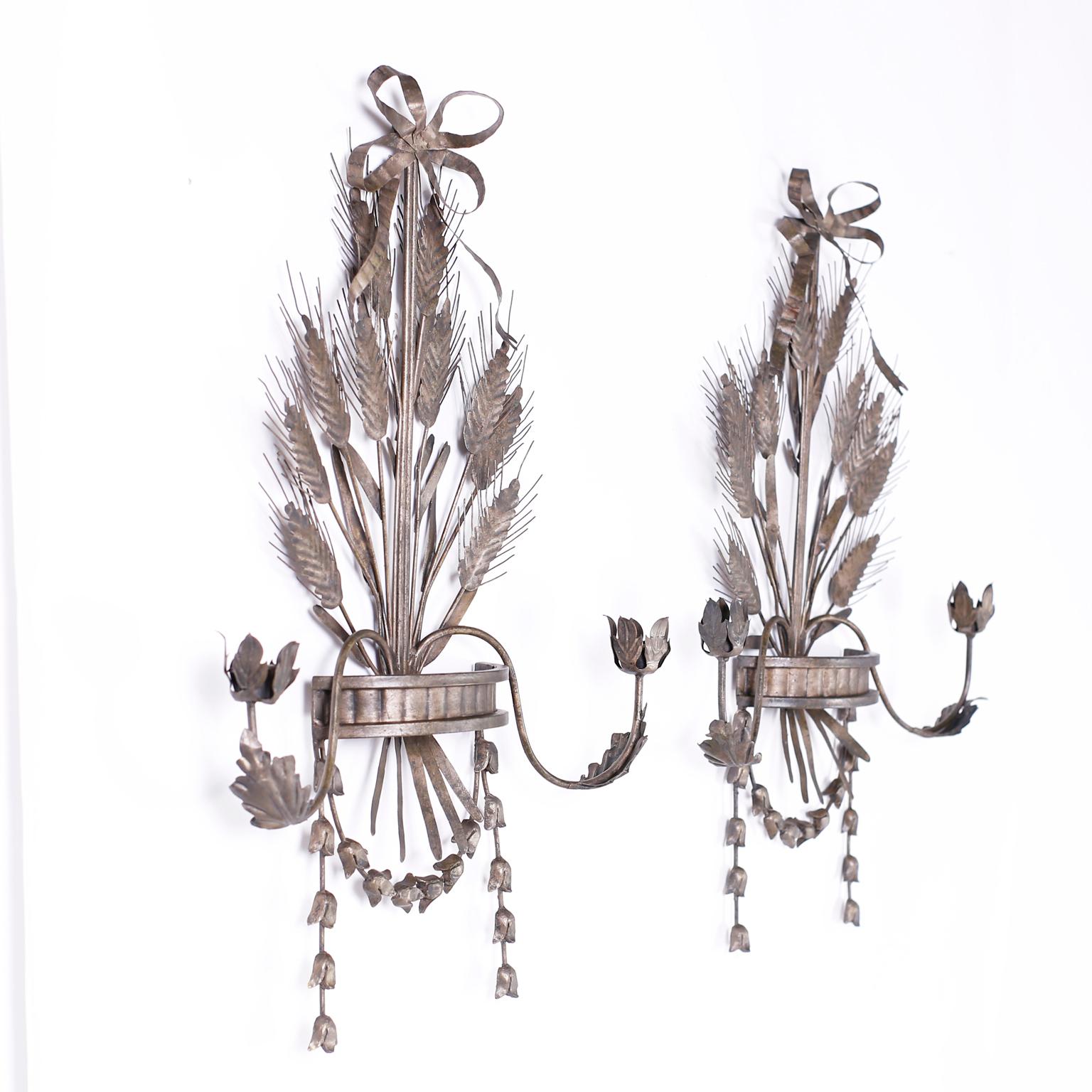 Unusual pair of metal two light wall sconces featuring ribbons, cattails, acanthus leaves and a sting of flowers, all with an old world worn gold washed finish.