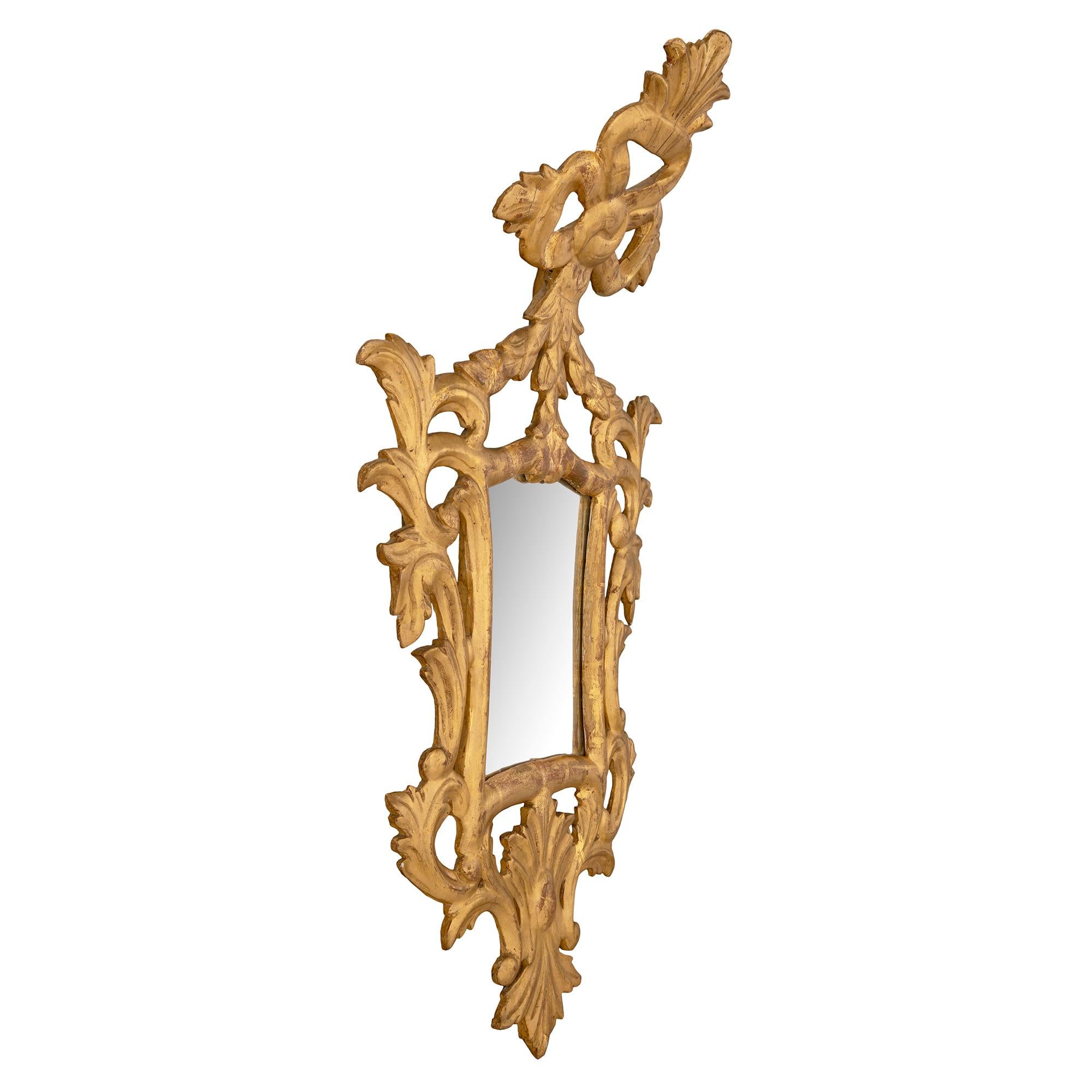 Atractiva pareja de espejos italianos de madera dorada de estilo barroco de mediados del siglo XVIII. Cada espejo veneciano conserva sus placas de espejo originales enmarcadas en un precioso borde moteado. Debajo están los elegantes cabujones lisos