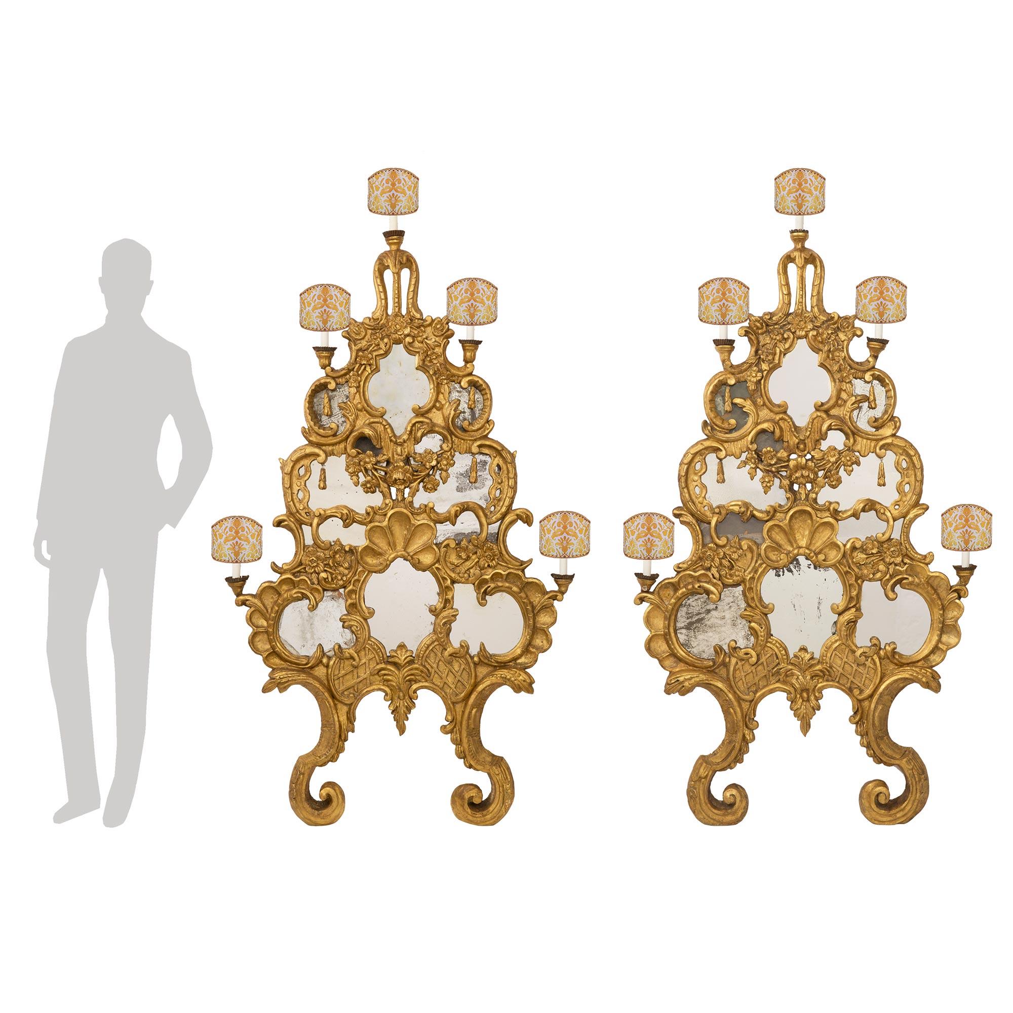 Une sensationnelle paire monumentale d'appliques baroques italiennes du milieu du XVIIIe siècle, à cinq lumières, en bois doré avec miroir, provenant de Venise. Chaque applique extrêmement décorative est dotée d'élégants supports inférieurs à