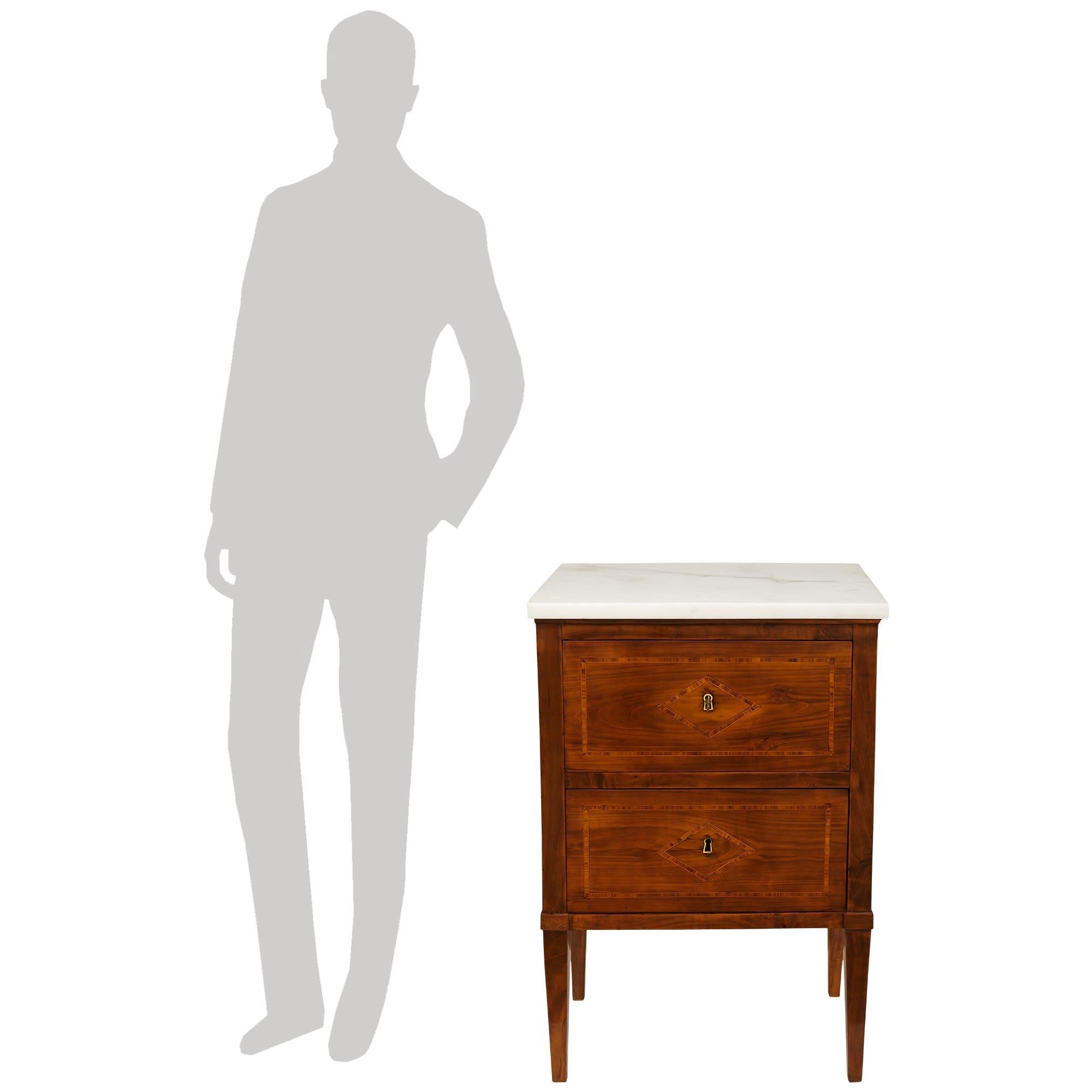 Una bella e molto decorativa coppia di commodes italiane della metà del XVIII secolo di epoca Luigi XVI in noce, tulipano e marmo bianco di Carrara. Ciascuna meravigliosa cassettiera a due cassetti è sollevata da quattro gambe quadrate affusolate