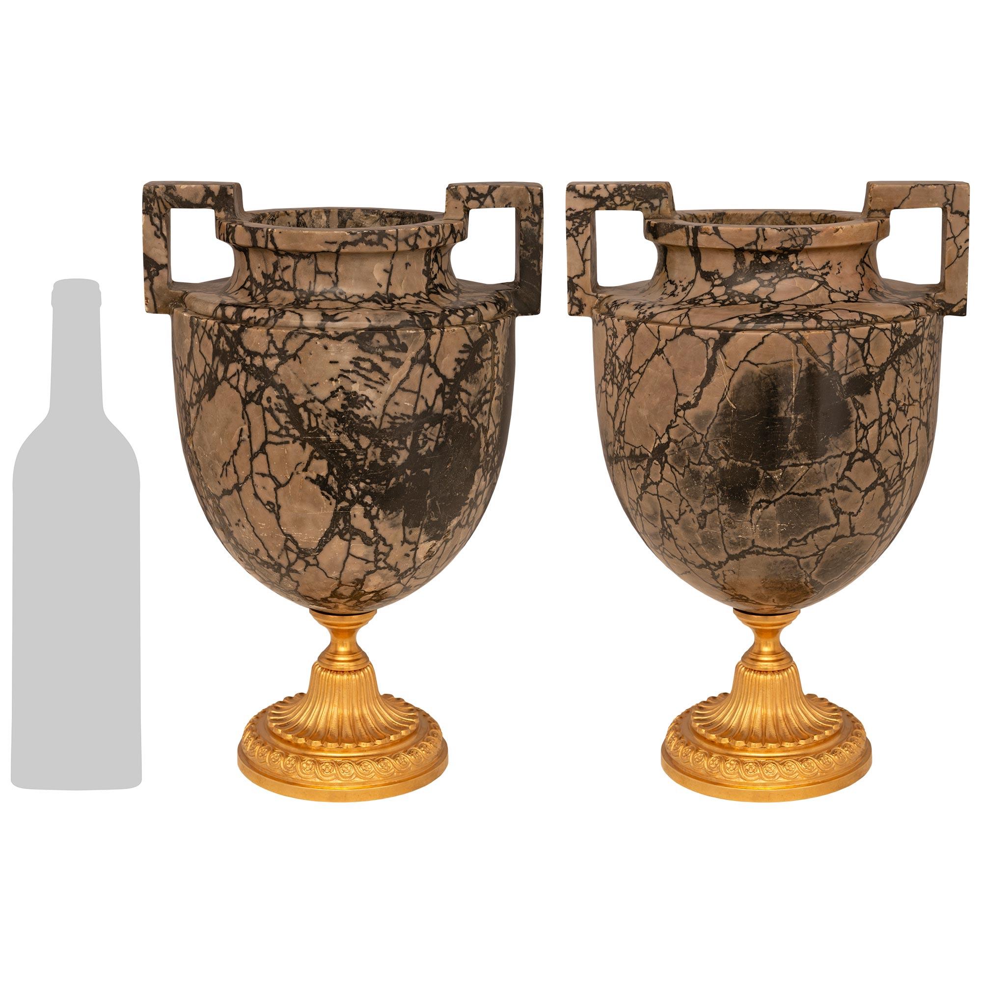 Una coppia molto attraente e di alta qualità di urne neoclassiche italiane della metà del XIX secolo. Marmo di Rain Forest e Ormolu. Ogni urna è sollevata da un supporto circolare in Ormolu riccamente cesellato con un bordo screziato decorato da una