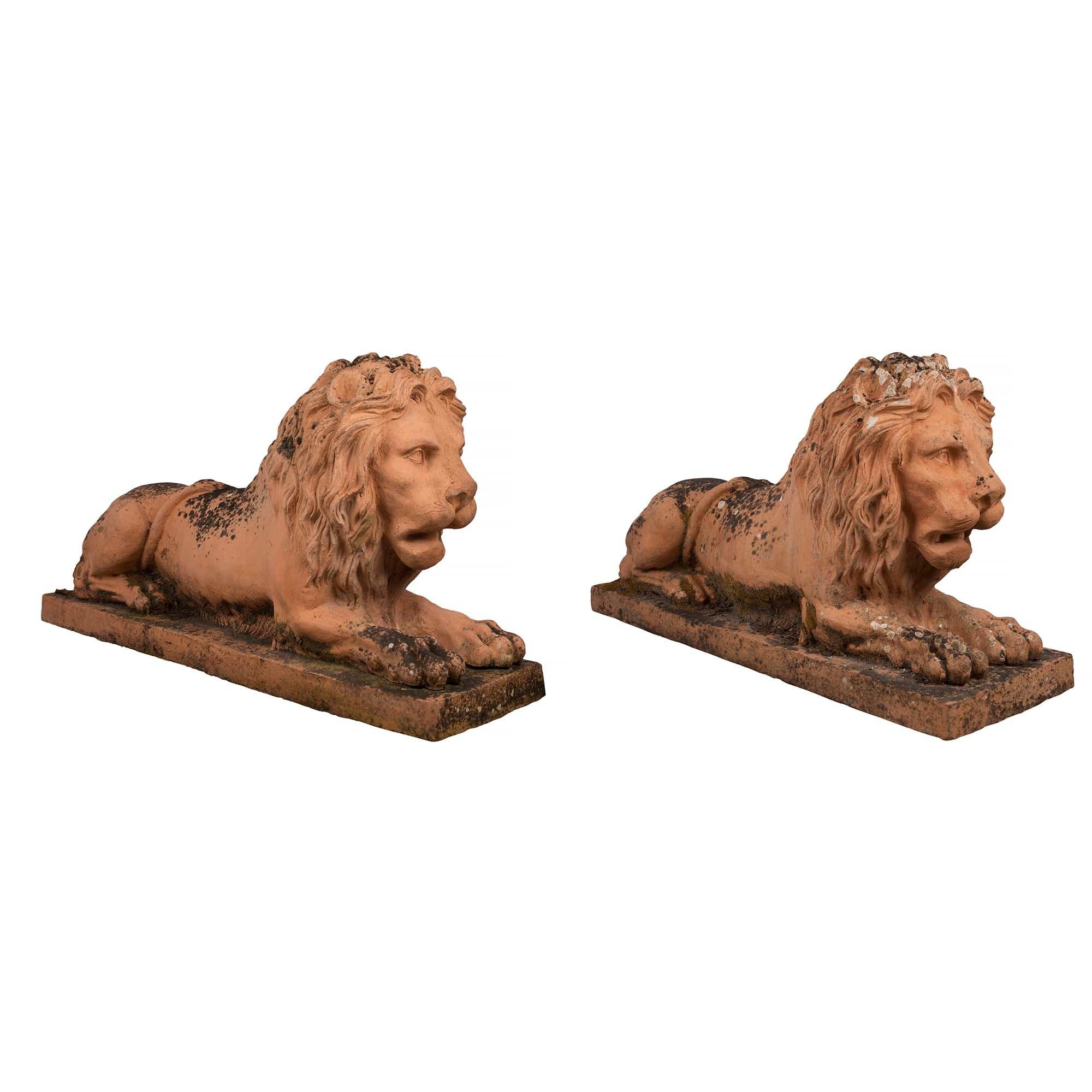 A sensational pair of Italian mid 19th century, circa 1850, terra cotta lions. Each lions is raised on a rectangular base. The lions with expressive faces and wonderfully carved manes, are sitting on their front paws. Outstanding patina throughout