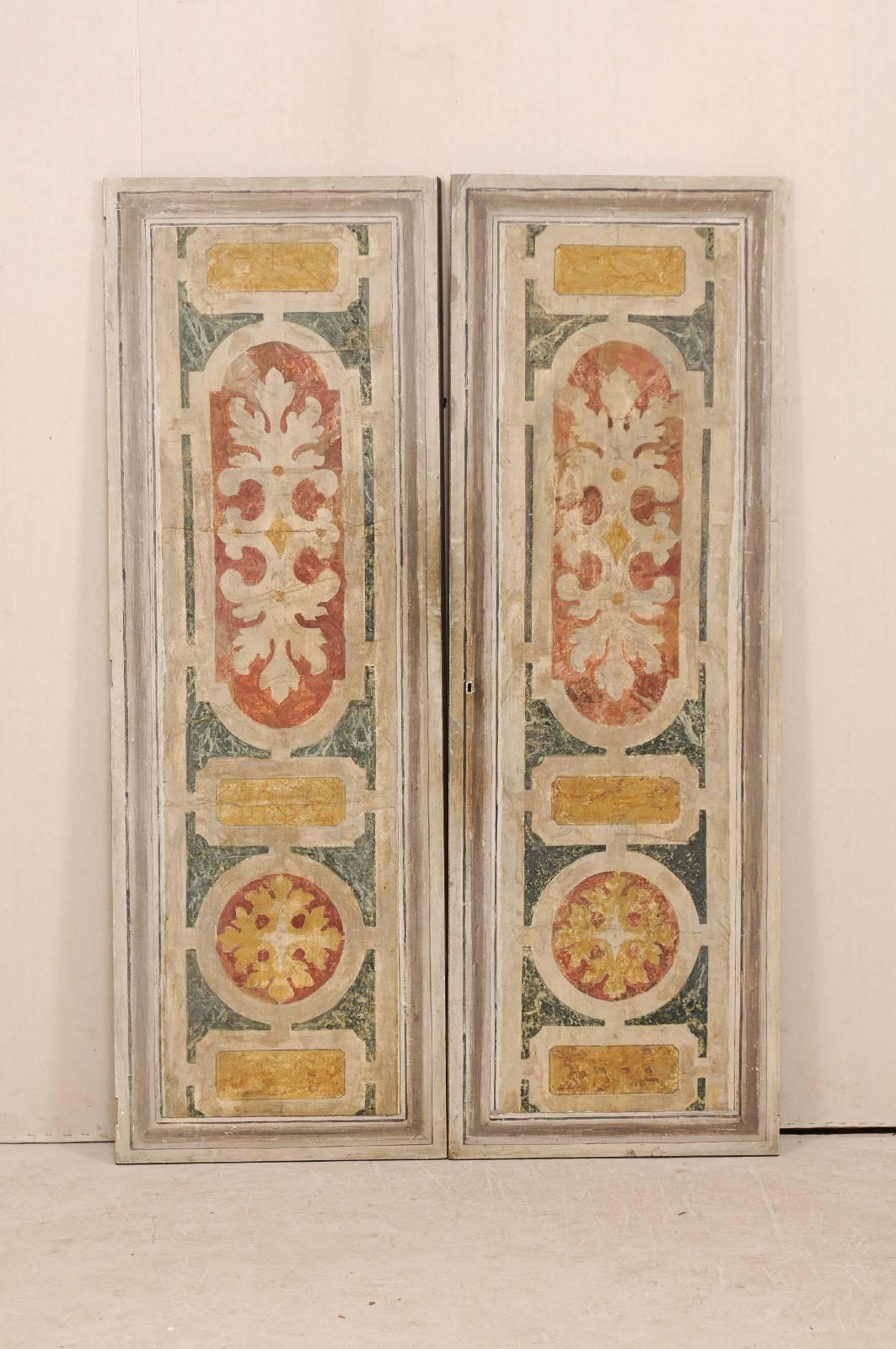 A pair of Italian wooden doors, decoratively painted, from the mid-20th century. This pair of vintage Italian doors feature a single front recessed panel painted with foliage and geometric designs in various shades of gray, muted gold, ocher red,