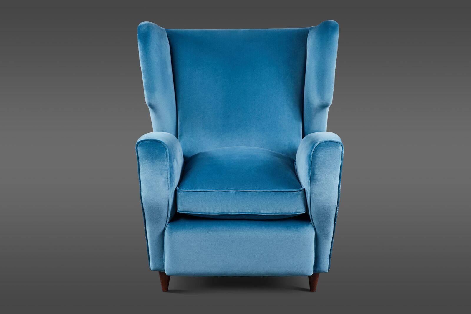 A curvaceous pair of Italian mid-20th century wingback armchairs in two tones of blue velvet with loose, overstuffed down and feather seat cushions.