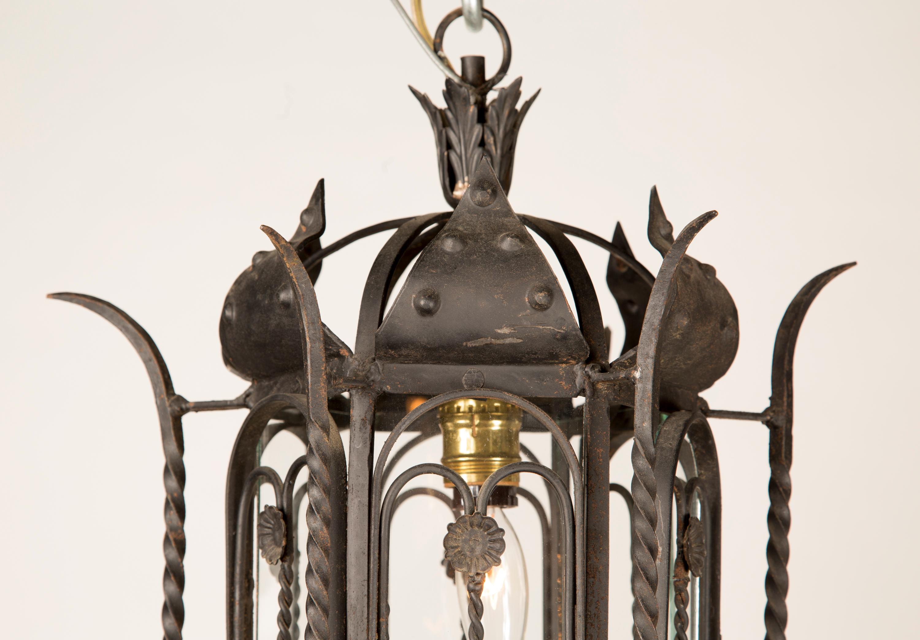 This beautiful pair of Italian hand painted wrought iron and glass hanging lanterns date back to the mid 20th century. The Italian pair features spiraling iron elements at center and a single central light. 

Each piece in our shop is professionally