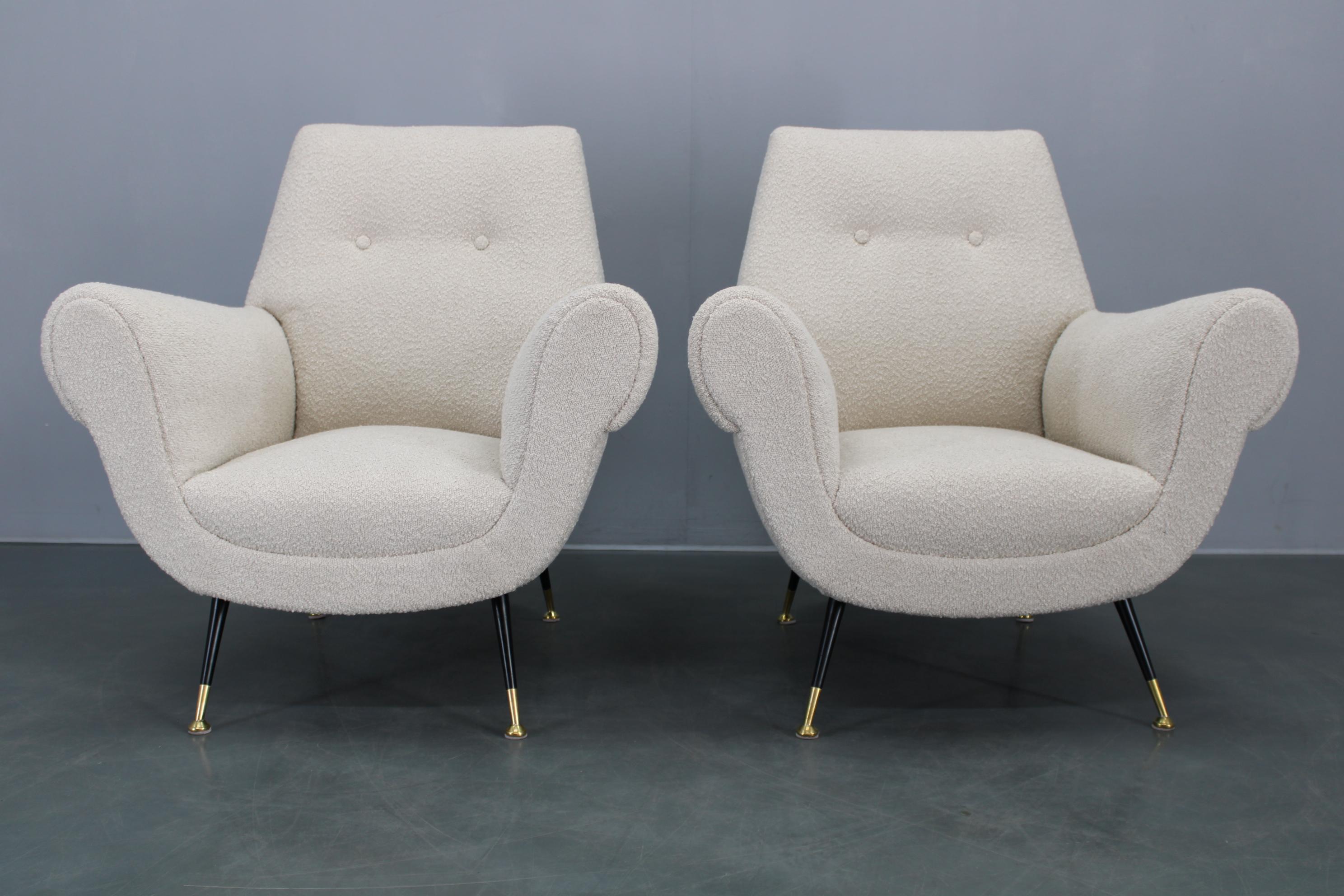 Zwei restaurierte italienische Sessel aus den 1950er Jahren mit neu gepolstertem Bouclé-Stoff, elegant geschwungenen Armlehnen und spitz zulaufenden, mit Messingspitzen versehenen Eisenbeinen. 
Die Struktur besteht aus massivem Buchenholz, das für
