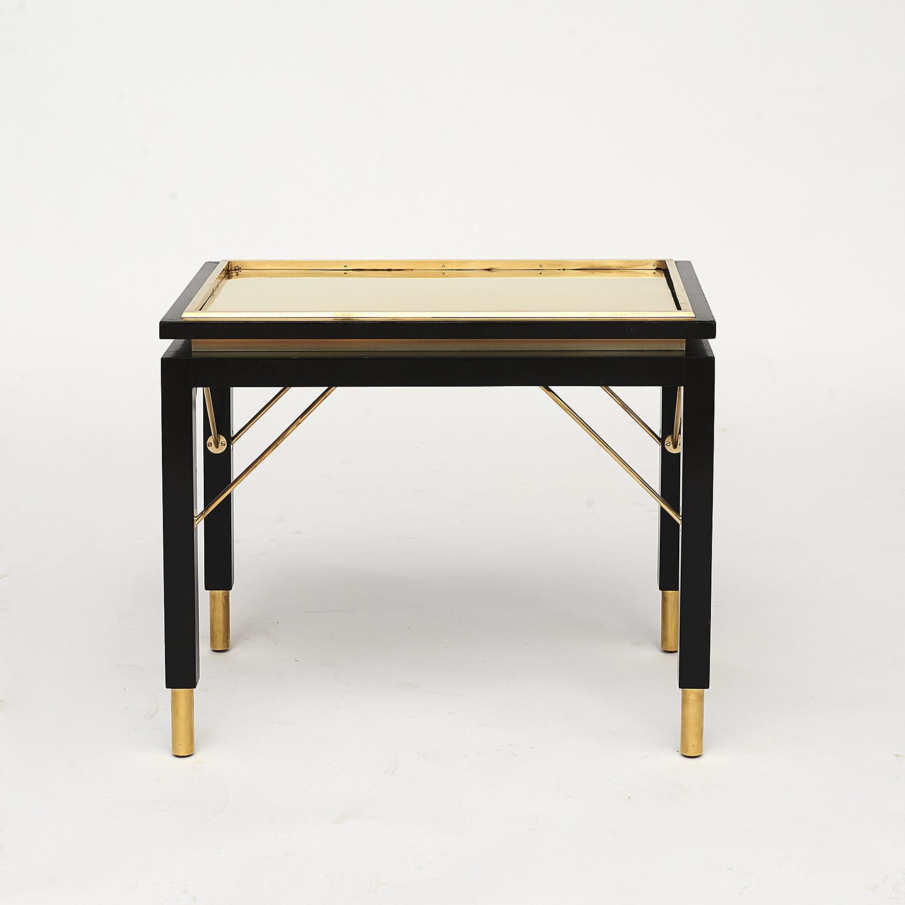 Pair of Italian brass side tables on black polished wooden frame with brass feet. Top with fixed edge and removable top plate,
Italy, 1950-1955.
Sold as a pair.
A sophisticated and timeless piece that will bring a contemporary twist to any