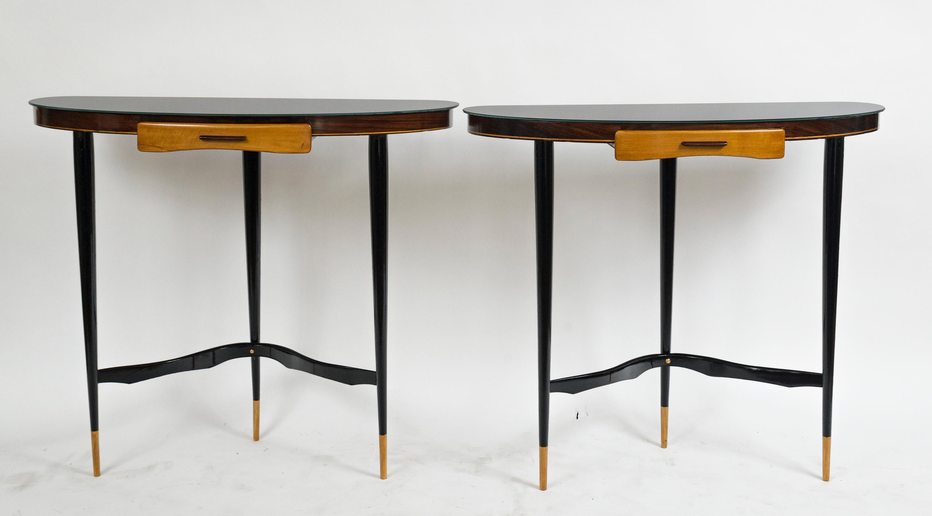 Unique pair of rounded d-shaped black glass top consoles with an ash drawer tucked in its sleek apron, finishing on three rounded tapered legs joined by a lacquered curved stretcher, legs painted black on pine and ash
In the manner of Ico