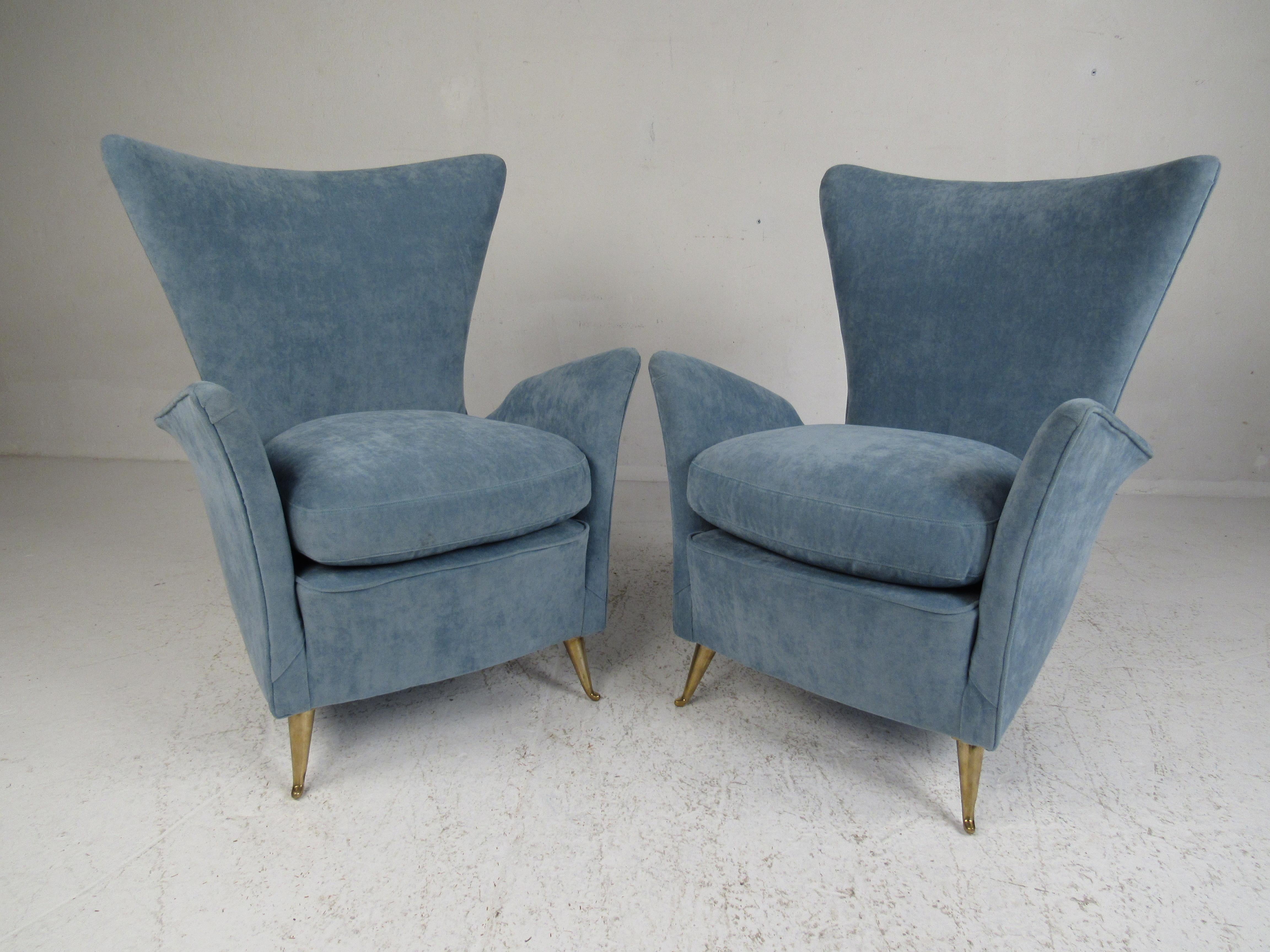 This beautiful pair of vintage modern Italian armchairs feature an impressive winged backrest and armrests. A sleek design that sits on splayed brass legs with unusual bent feet. The thick padded seats are covered in plush light blue fabric. This