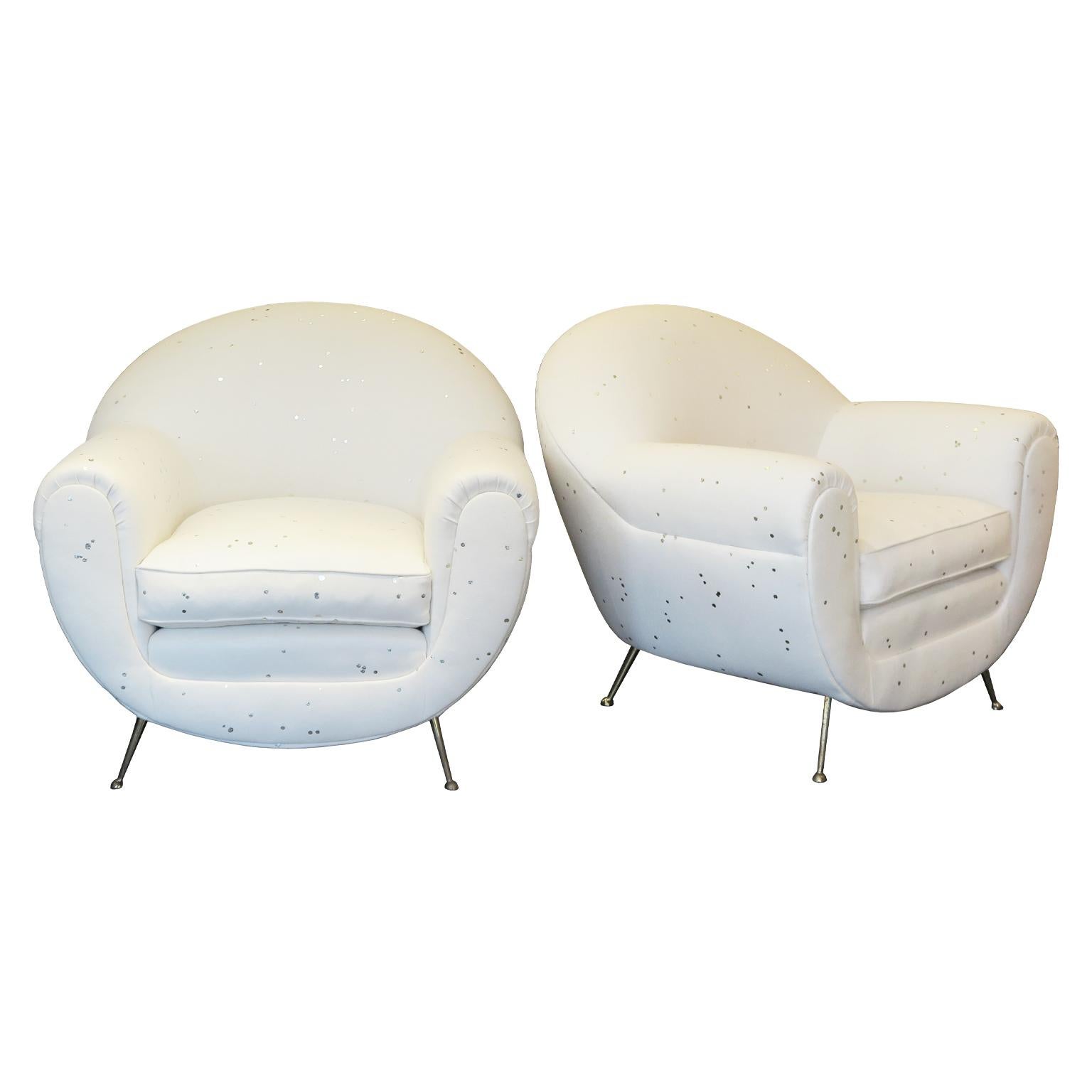 Pair of Mid-Century Italian Lounge chairs. These stylish newly upholstered armchairs feature a rounded shape with a wool fabric in a soft cream coloration with white-gold dots all around. The chair showcases tapered brass legs adding a lightness to