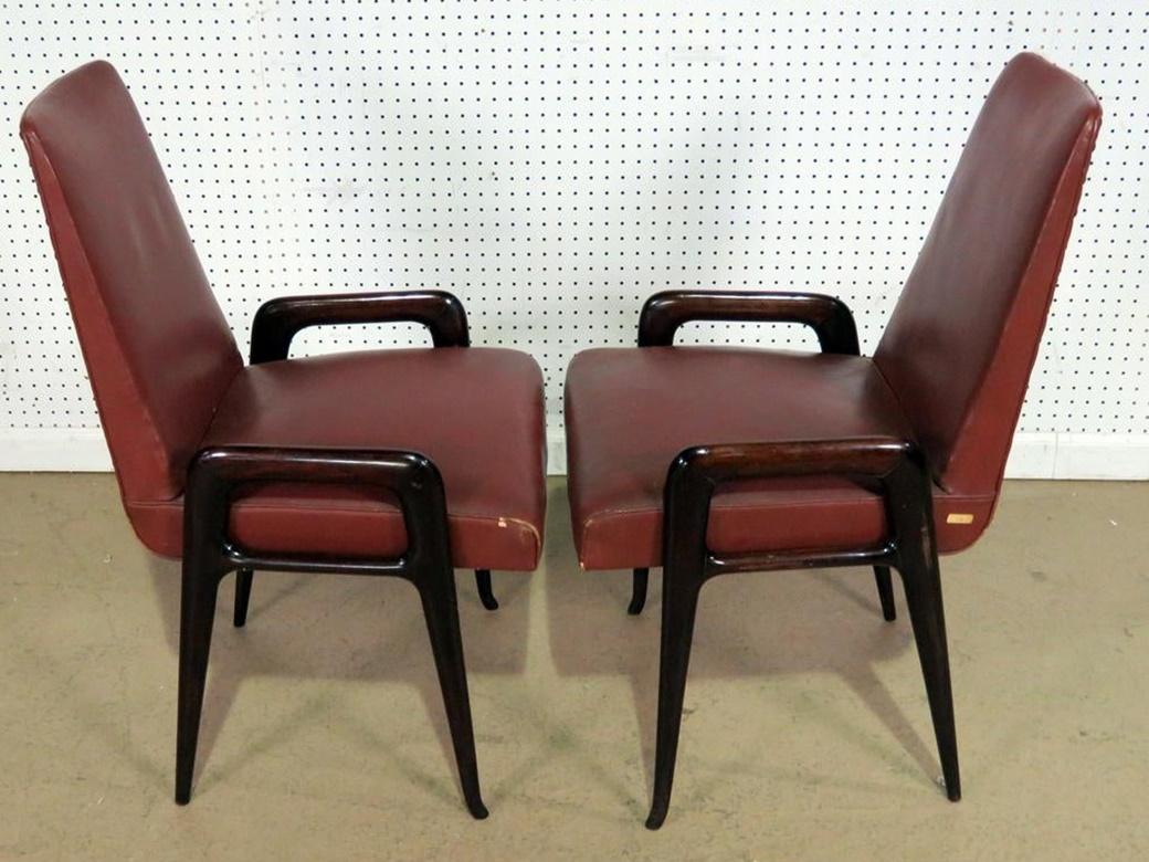 Pair of Italian distressed leather and rosewood Mid-Century Modern armchairs with nailhead trim.
