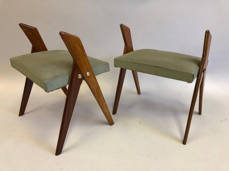 Rare and exceptional pair of Italian Mid-Century Modern wood stools or benches featuring pairs of angled and tapered saber legs that unite to support seats. Solid brass pins and leg detailing complete the composition.

Seats coverings are original