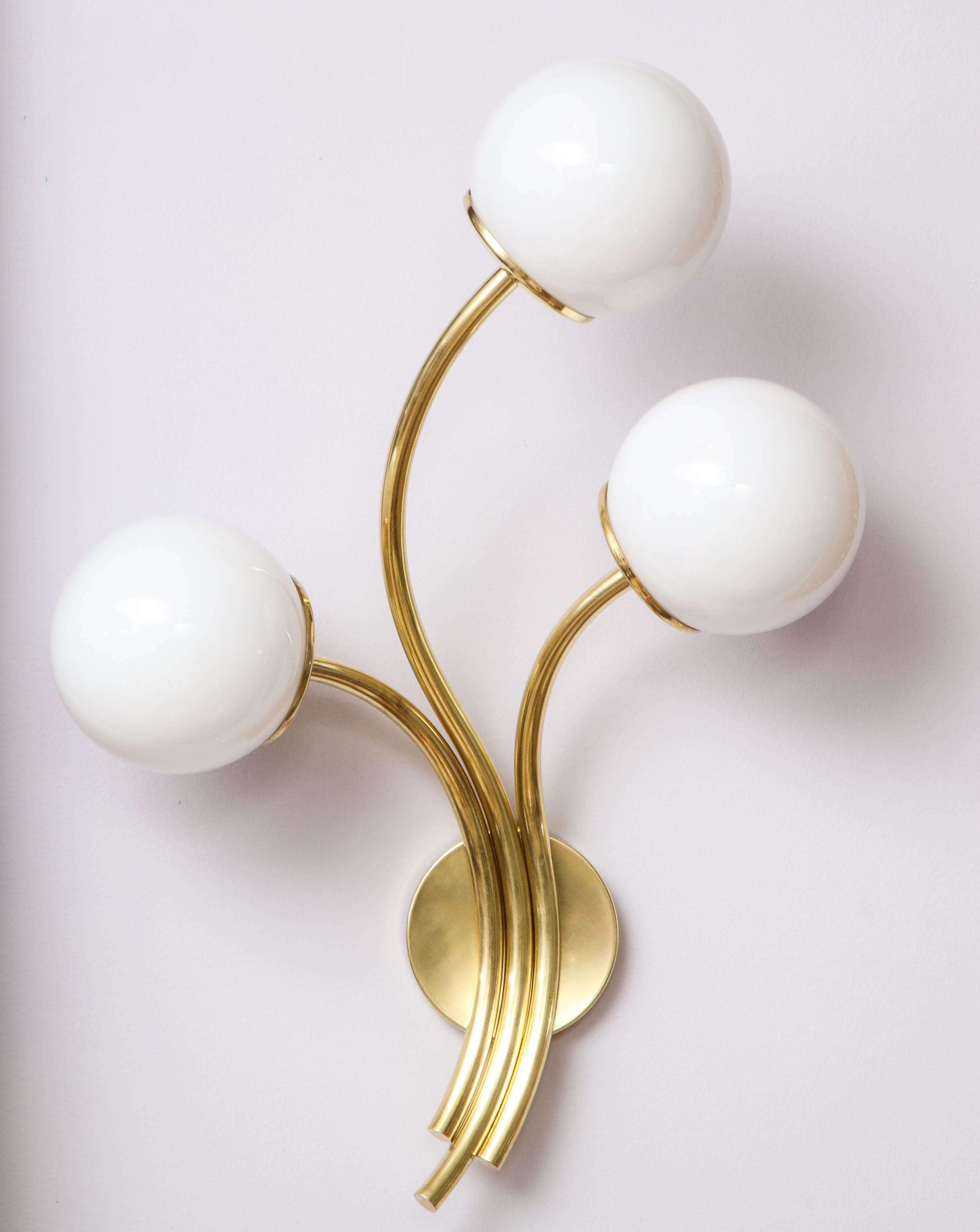 Pair of Italian three-light brass and opaline glass globe wall sconces. The three sconce arms extending from a wall-mounted circular brass plaque. Beautiful and organic design. (Re-wired for USA standards). 
Italy, circa 1950.
Size: 20