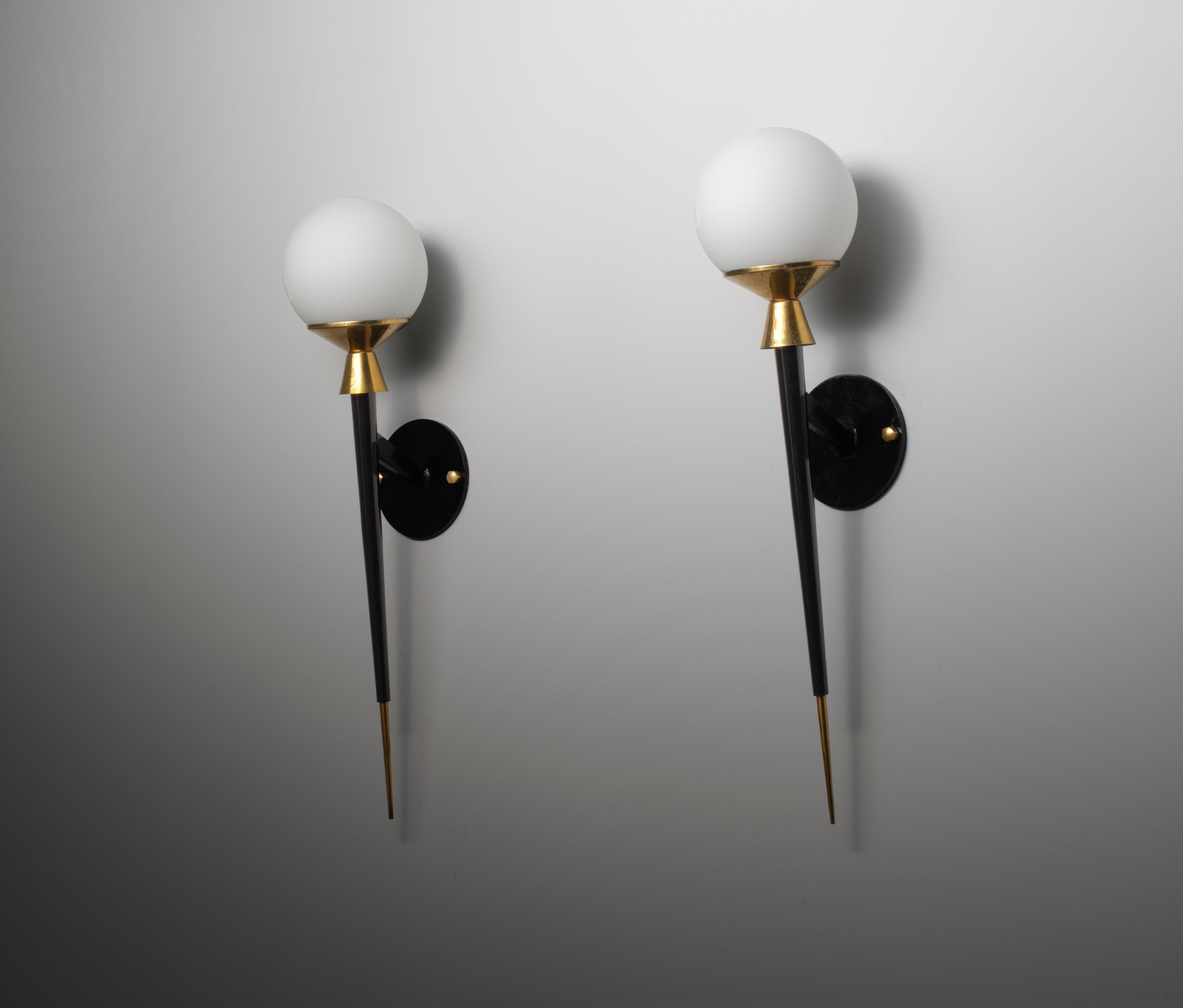 Pair of elegant Italian wall sconces, designed and produced in the 1950s, reflecting a sophisticated Mid-Century Modern aesthetic. Each sconce is crafted with a slim black enameled iron stem, accented by brass details exhibiting a pleasing patina.