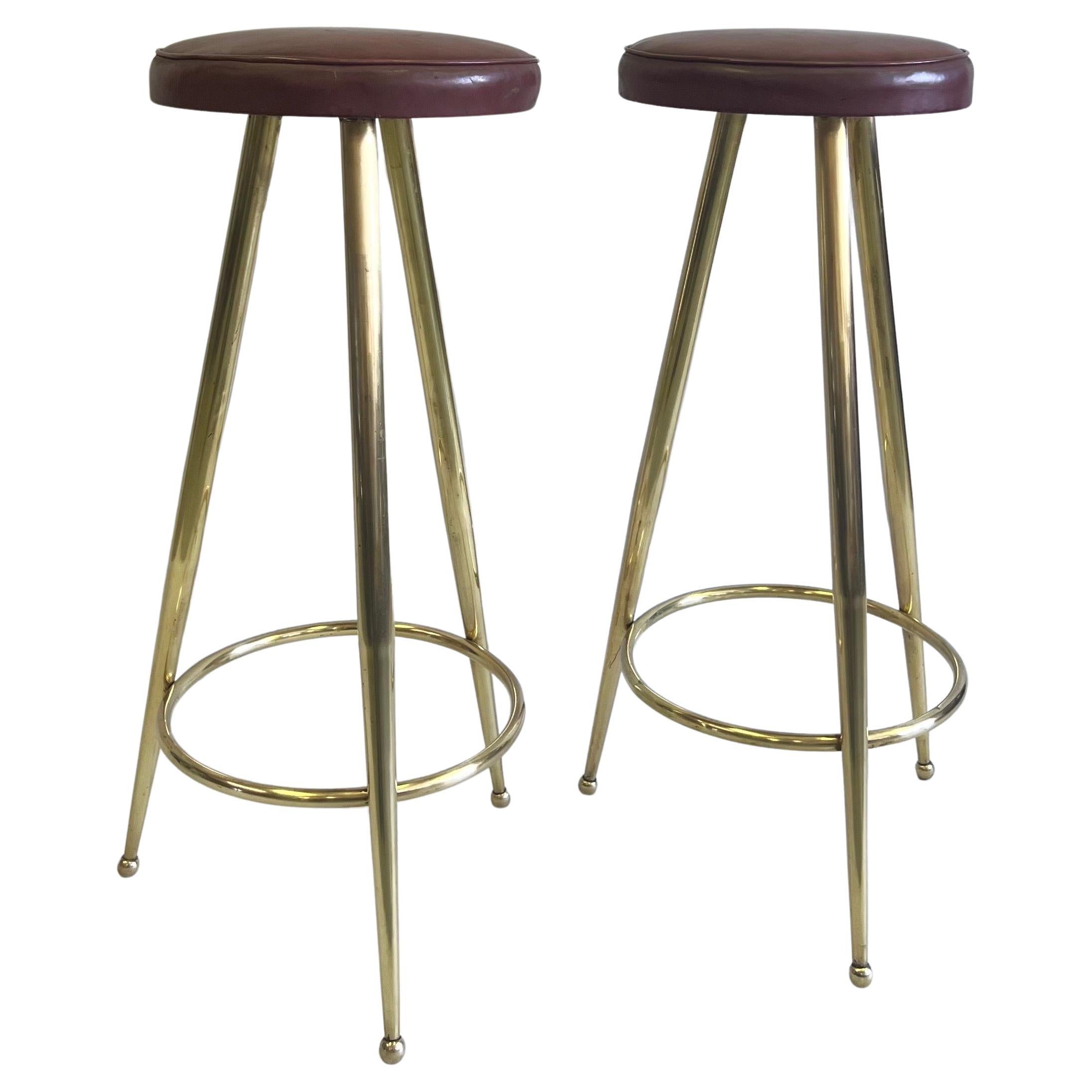 An Elegant and Timeless Pair of Italian Midcentury Modern Bar Stools in Solid Brass by Gio Ponti. The bar stools present an open, transparent aesthetic with pure lines and sober details. They are comfortable and practical while maintaining their