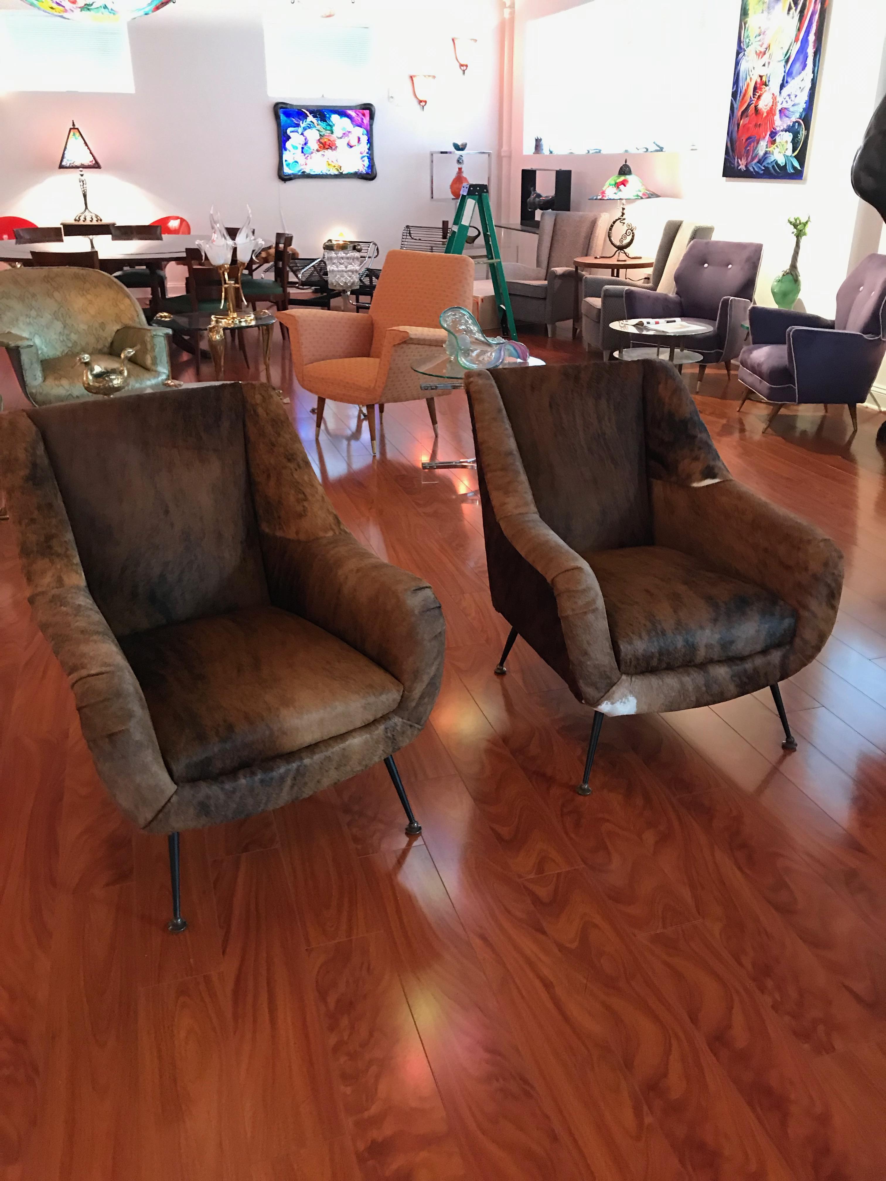 A pair Italian Mid-Century Modern club chairs reupholstered in cow hide, circa 1960. These are great for any room and are extremely comfortable. The cowhide is in amazing condition.