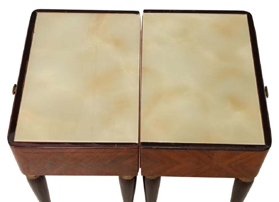 Pair of Italian mid-century modern lacquered wood nightstands, c.1950s, having reverse painted glass top, over single drawer, with scrolled foliate marquetry and inlaid banding, rising on tapered legs, ending in brass cap feet