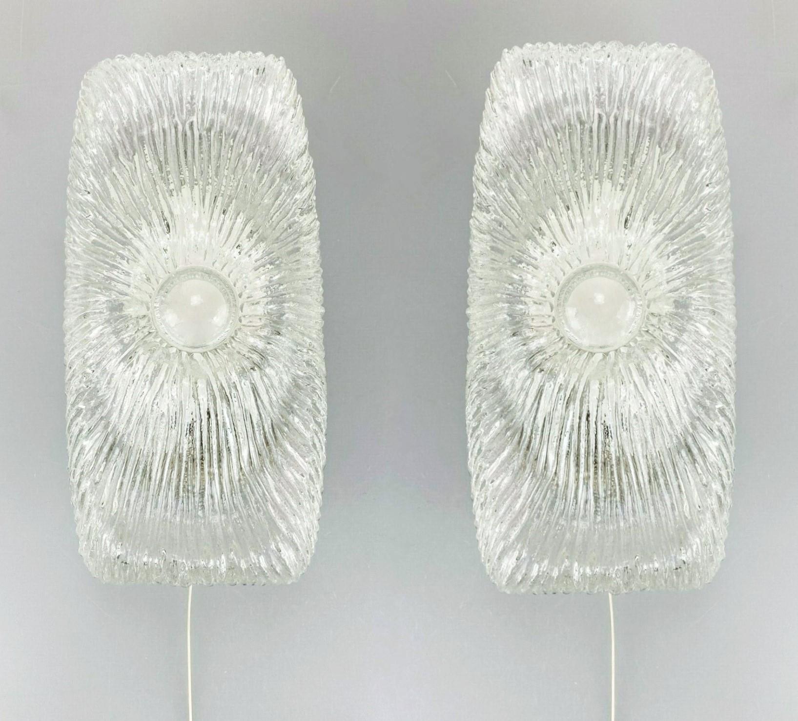 Beautiful pair of vintage midcentury Murano ice glass wall lights, Italy, 1960-1965. Modernist textured clear iced glass shades with black metal frames, one ceramic light socket. For a E14 screw bulb up to 60Watt (each sconce).
The glass shades