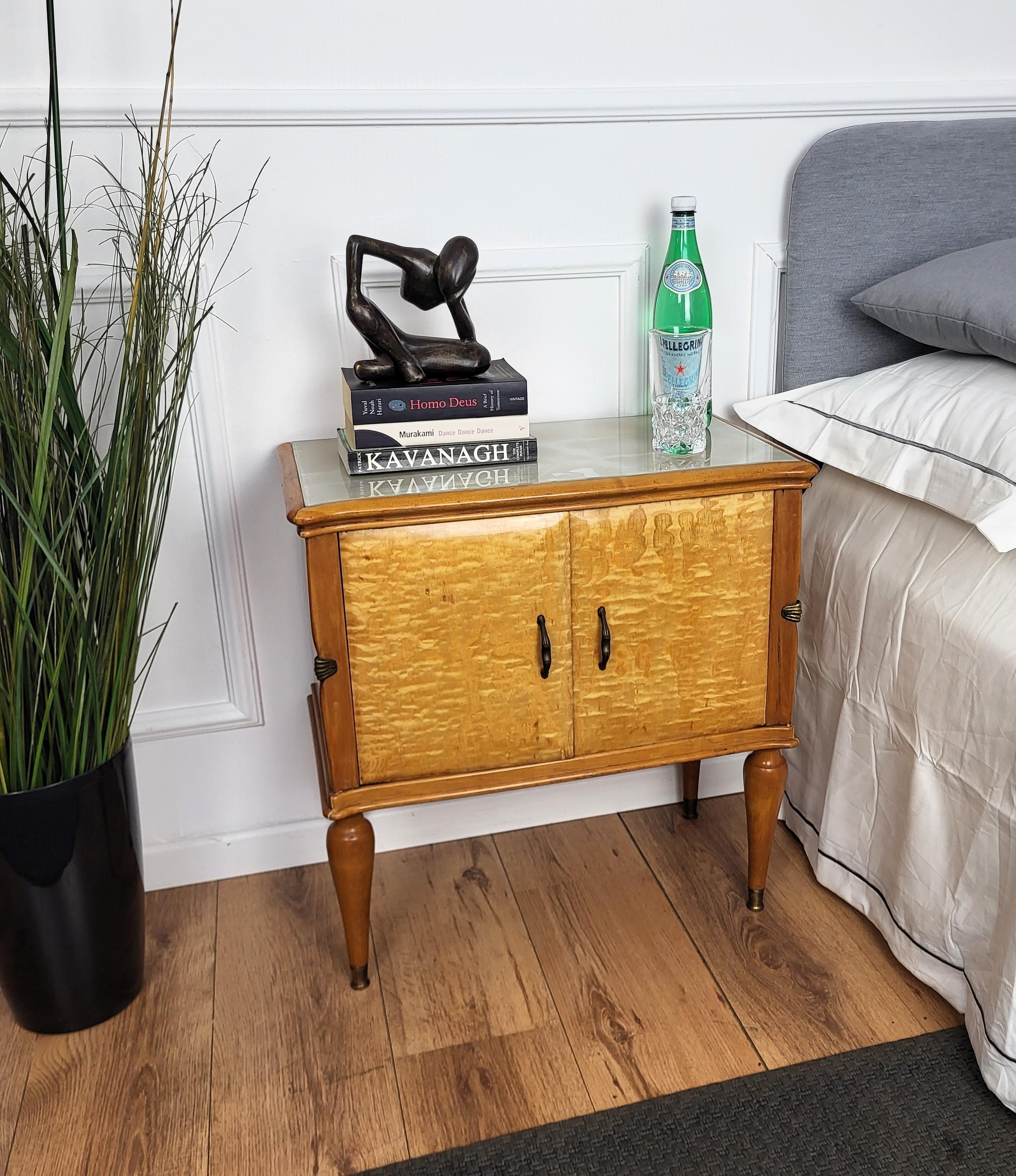 Very elegant and refined Italian 1950s Mid-Century Modern pair of bedside tables with great design of the white maple wood on the frontal door with brass handles and lacquered glass top. The great vintage shape and design, as well as the brass