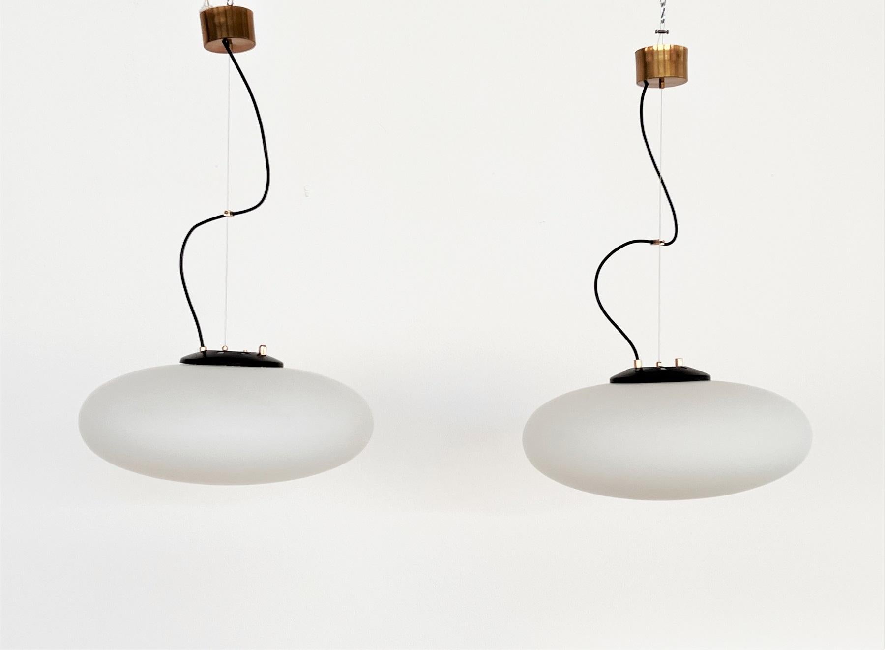Gorgeous pair of two pendant lights with stunning opaline glass Made in Italy by Stilnovo.
The pendants are fixed with steel cable (new) and original ceiling rose in dark brass to the ceiling.
Both lights come from the same household and are in