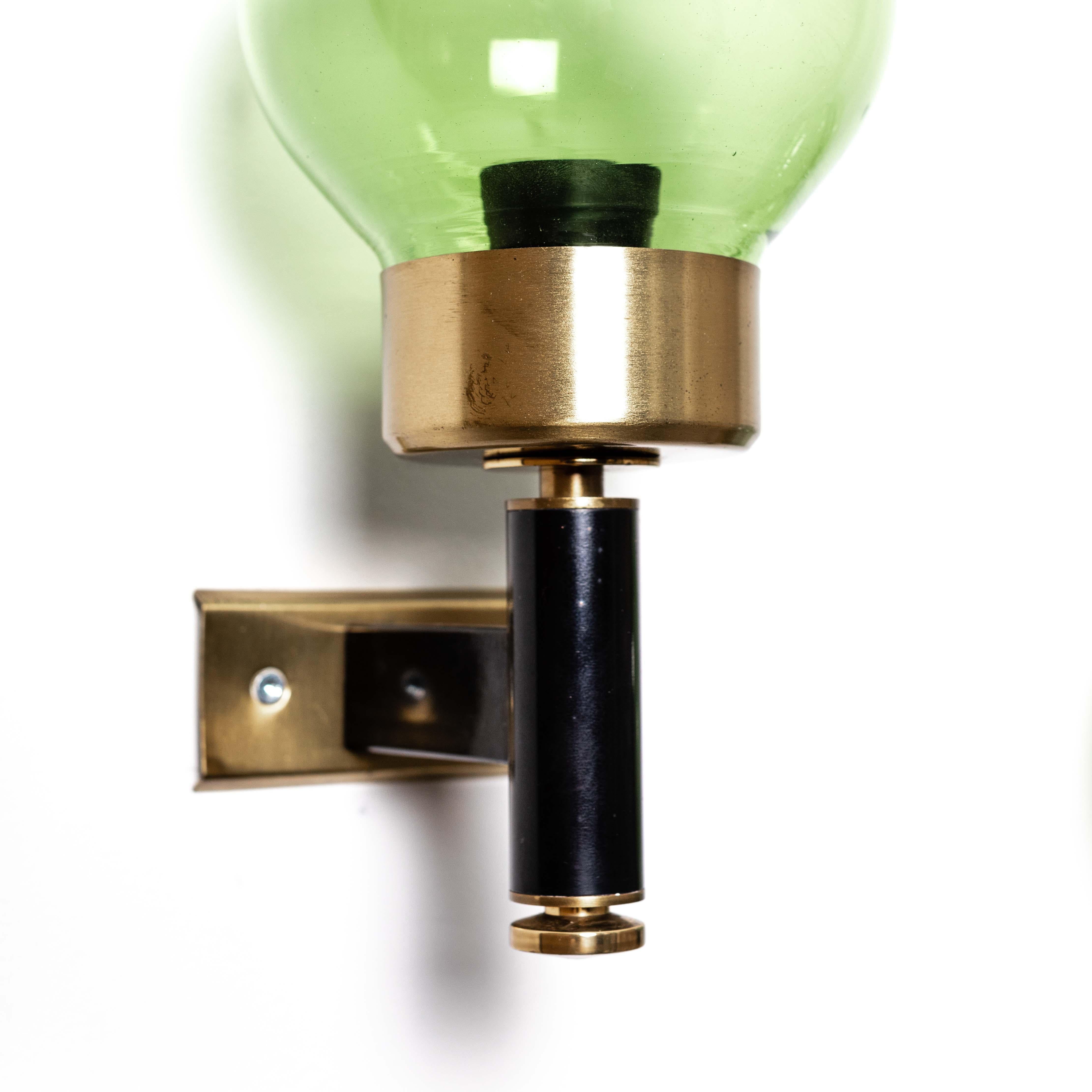 Dating from the 1960-ies, these Italian wall lamps stand out for their clean lines and green glass shades.
The rectilinear central spar is painted black, down with a small heel a slightly tapered brass finish. 
To the top, also with a small spacer