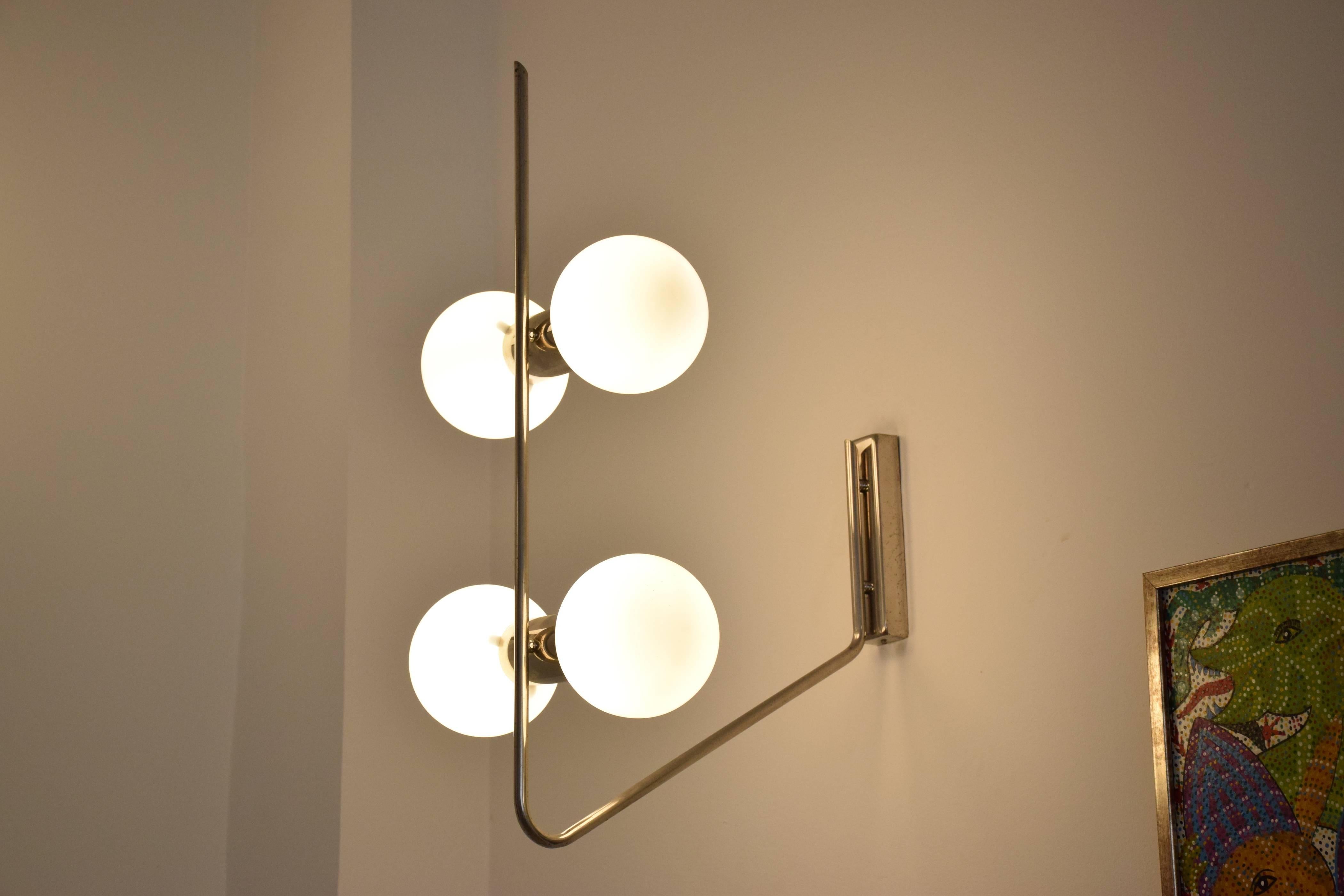 Pair of Italian 20th century vintage wall lights or sconces attributed to Stilnovo circa 1960s-1970s designed with a slender chrome stem and four symmetrical boule shaped white opaque shades of Space Age design.
Each glob can hold 40 - 60 watts so