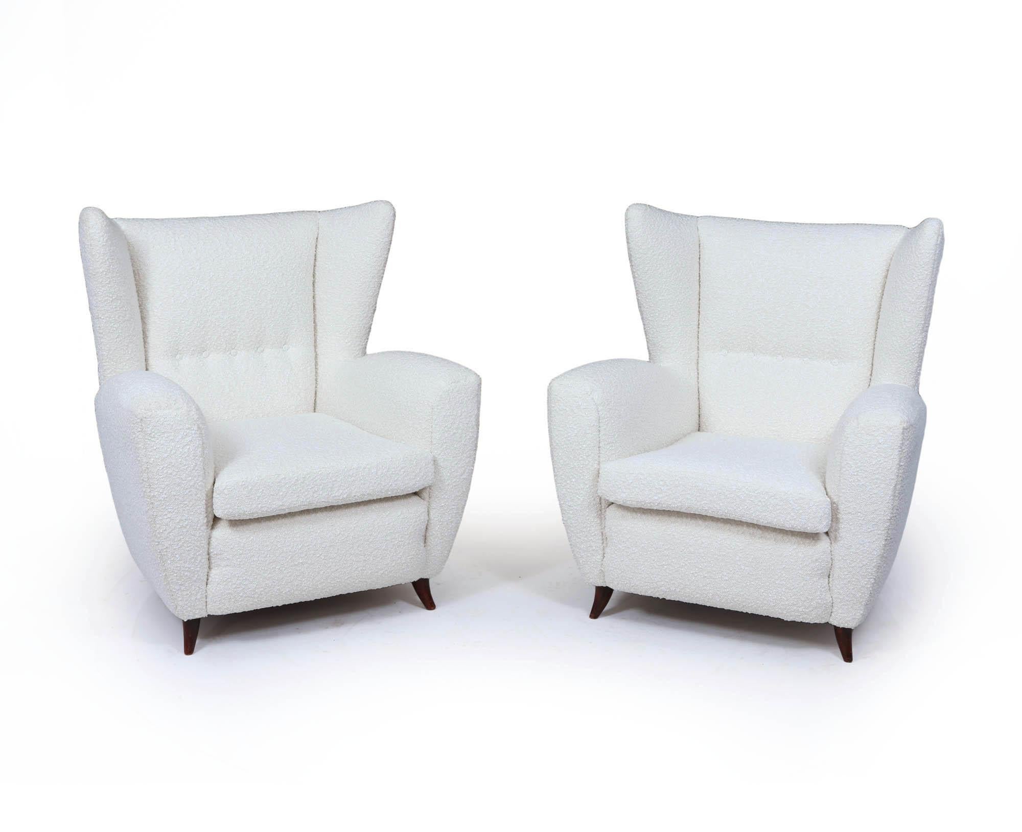 Une paire sculpturale et accueillante de fauteuils italiens du milieu du siècle, récemment retapissés dans un luxueux bouclé ivoire. Datant des années 1950, ces chaises de salon à haut dossier présentent des silhouettes ailées spectaculaires, des