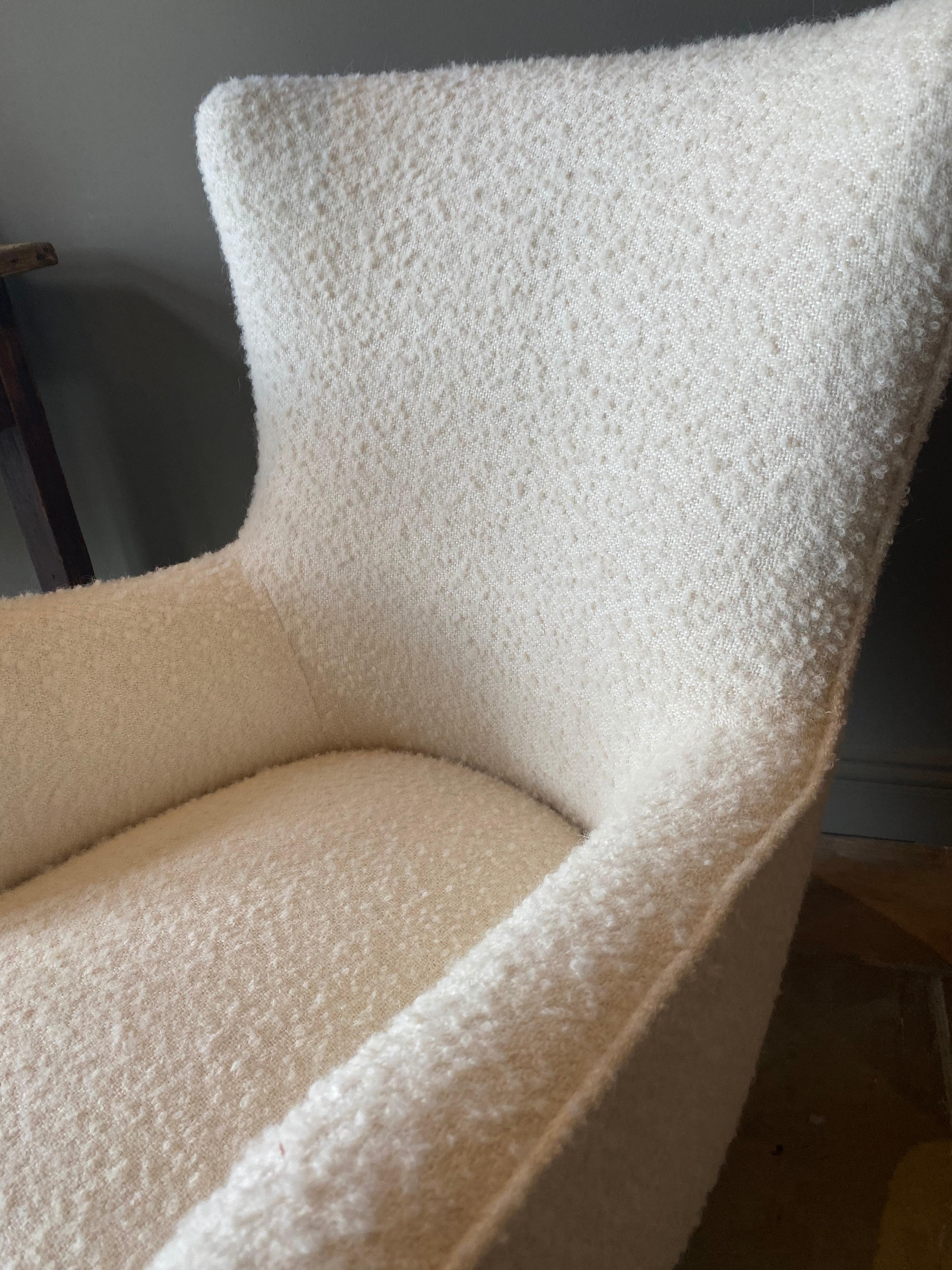 Elegant pair of Italian mid-century wingback chairs newly upholstered in Rogers & Goffigon creamy white boucle.