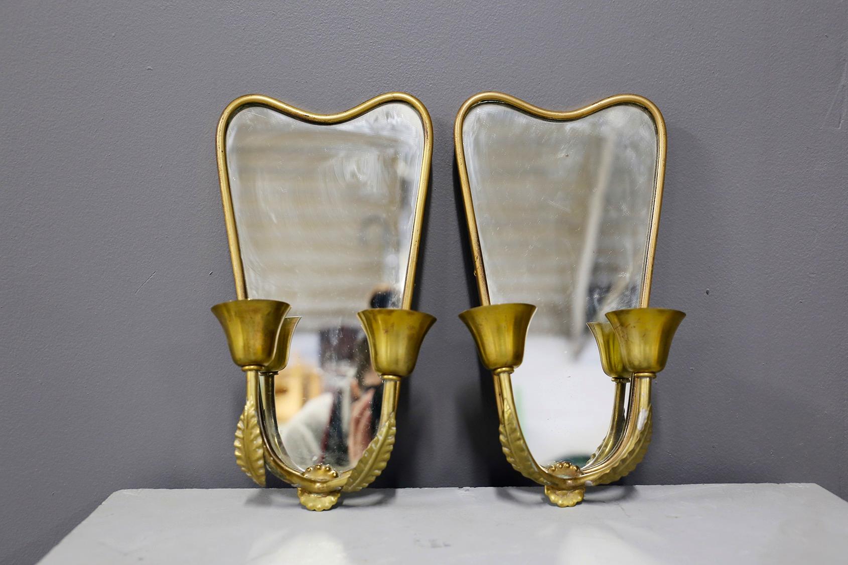 Pair of small Italian wall lights from 1950. The wall lamps, as can be seen from the photographs, serve as a double function. In fact, thanks to the mirror stuck in the inside of the brass frame you can also mirror yourself. The mirror is